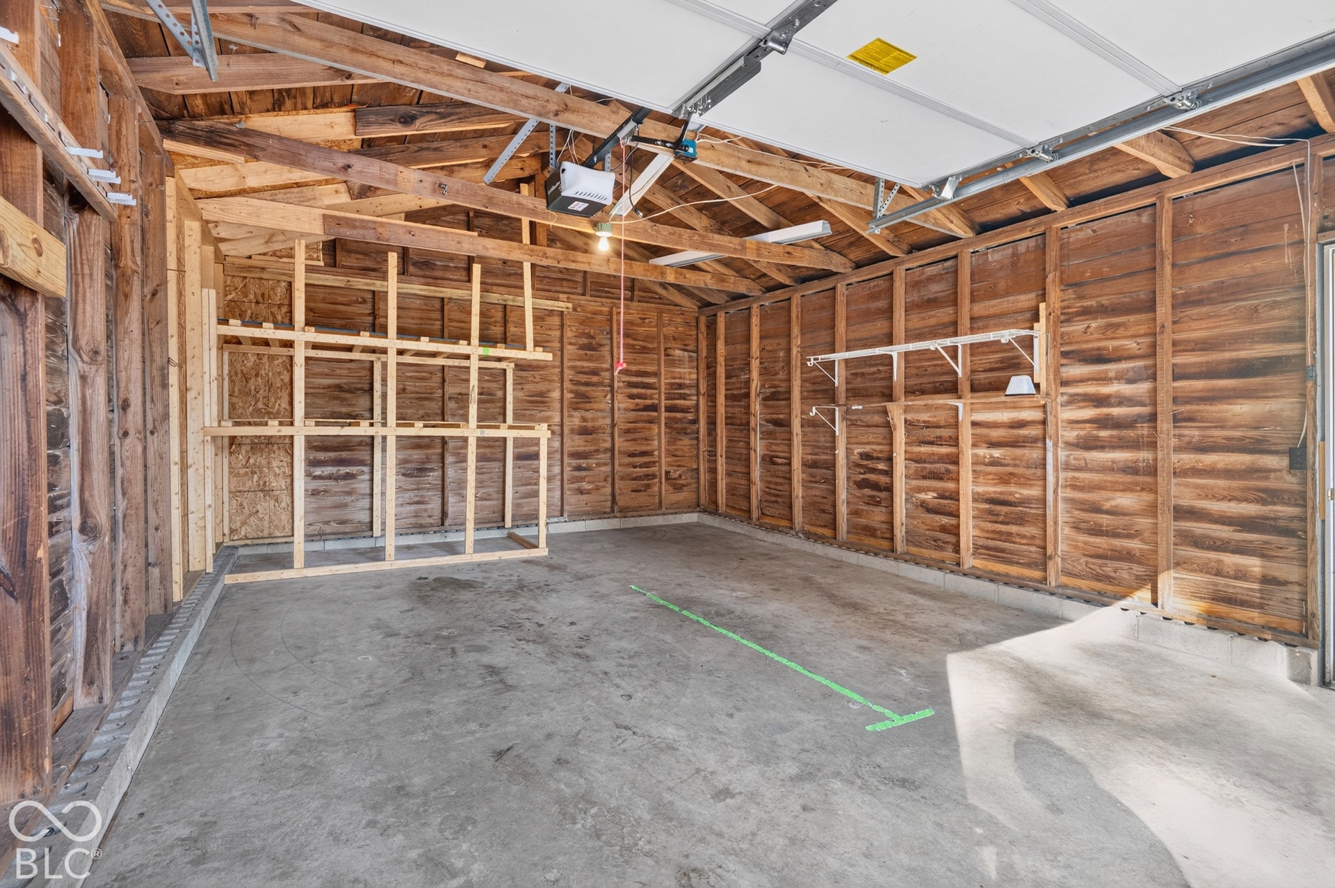 2706 13th Street, Columbus, IN 47201 Spacious garage interior featuring exposed wood-beam ceiling construction, concrete flooring, wood-paneled walls, and recessed lighting throughout