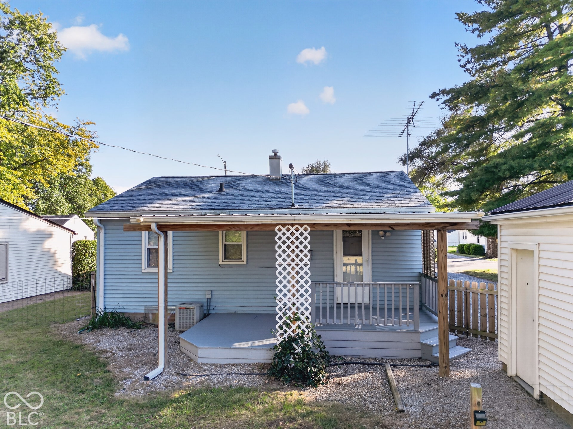 2706 13th Street, Columbus, IN 47201 Rear exterior featuring light blue horizontal siding, a covered deck with lattice supports, and graveled grounds