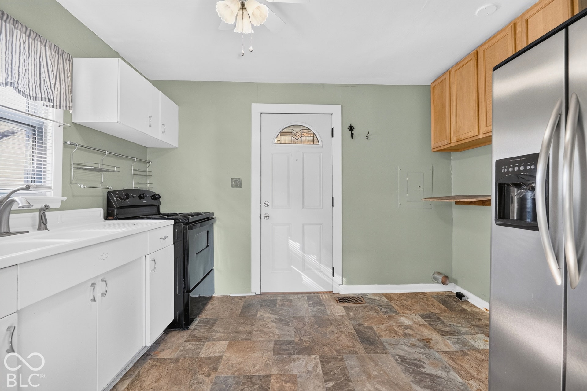 2706 13th Street, Columbus, IN 47201 Spacious kitchen featuring white cabinetry, stainless steel appliances including a refrigerator and electric range, wood-finish flooring, sage green walls, and abundant counter and storage space
