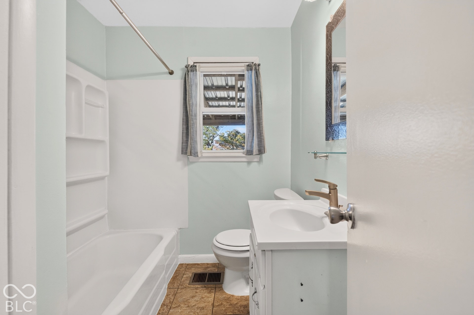 2706 13th Street, Columbus, IN 47201 Bathroom featuring a white vanity with integrated basin, metallic faucet, tiled flooring, and a tub-shower combination with surround