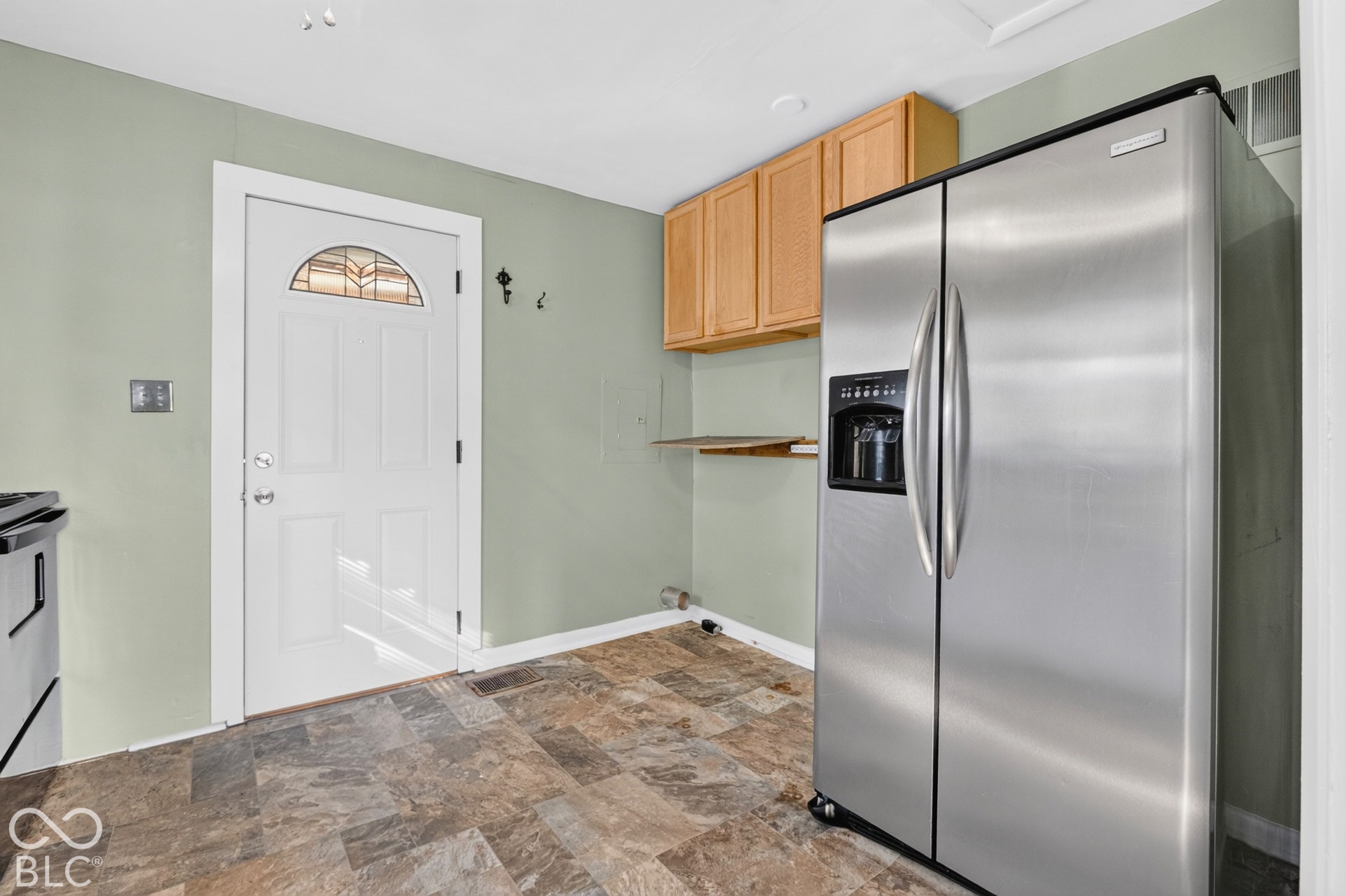 2706 13th Street, Columbus, IN 47201 Stainless steel side-by-side refrigerator, shaker-style wood cabinetry, exterior door with decorative glass insert, and tile flooring