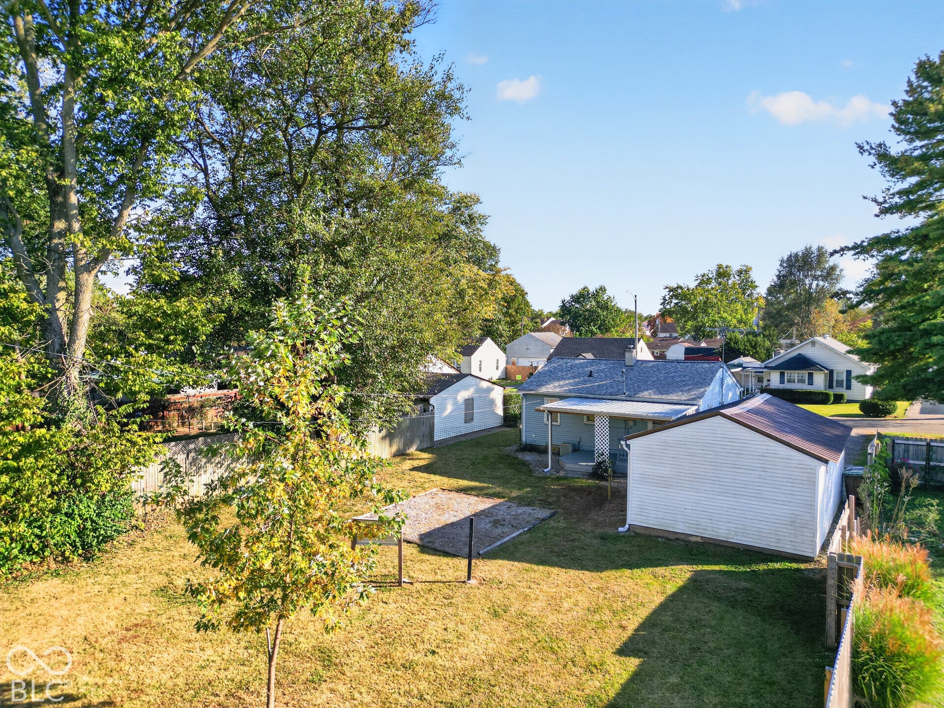 2706 13th Street, Columbus, IN 47201 Backyard space featuring mature trees, a detached storage structure, a paved ground-level area, and perimeter fencing