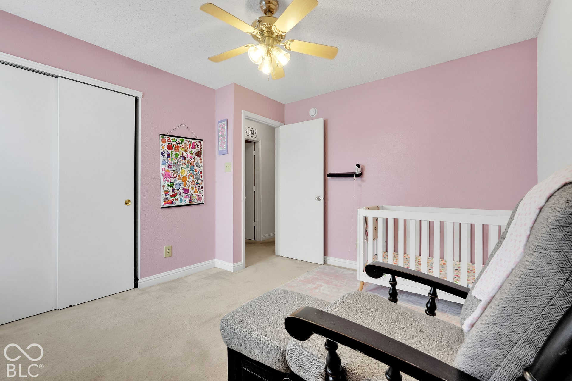 Wall-to-wall carpeting, ceiling fan with light fixture, and white bi-fold closet doors