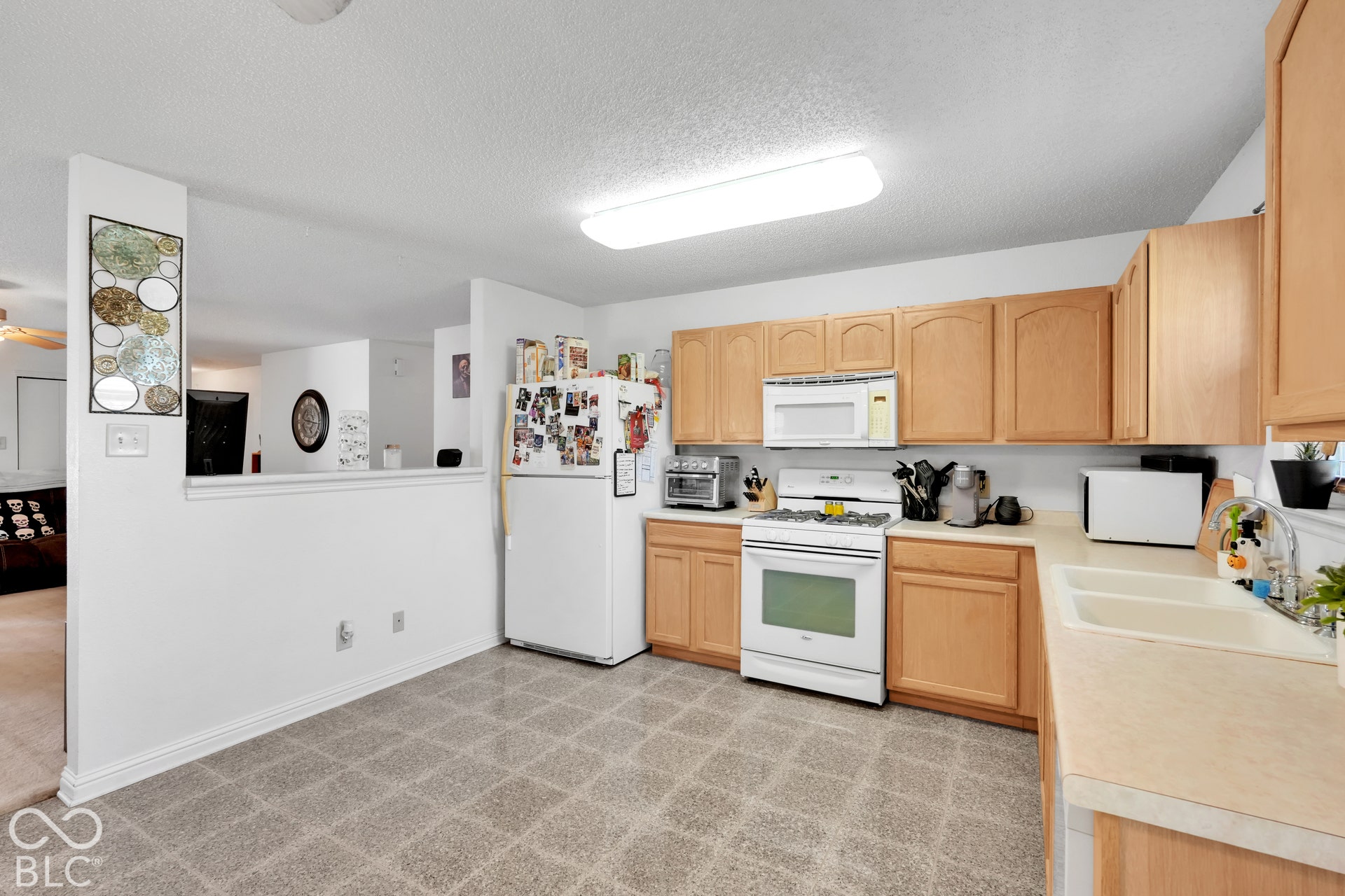 Kitchen featuring wood-finish cabinetry, white appliances, dual basin sink, and ample countertop space