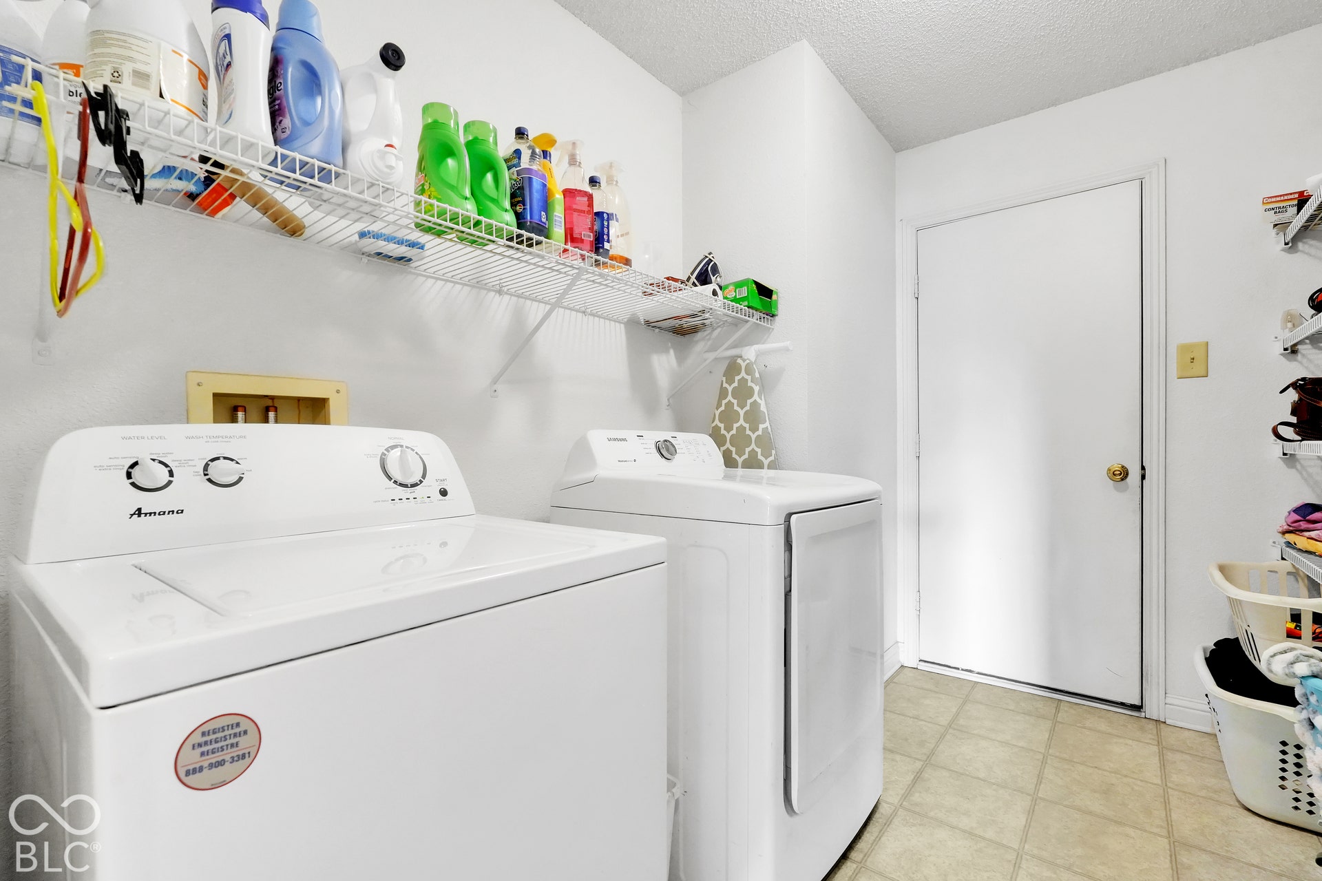 White walls with overhead wire shelving, light-toned flooring, and a white door with a round doorknob