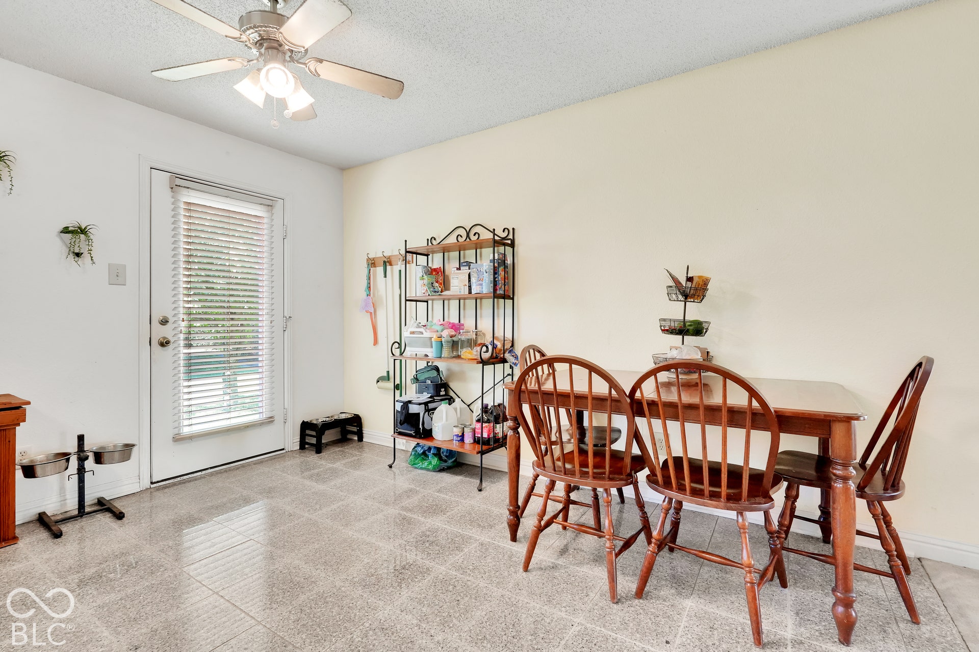 Ceiling fan with integrated lighting, white walls, light-colored flooring, rear door with blinds