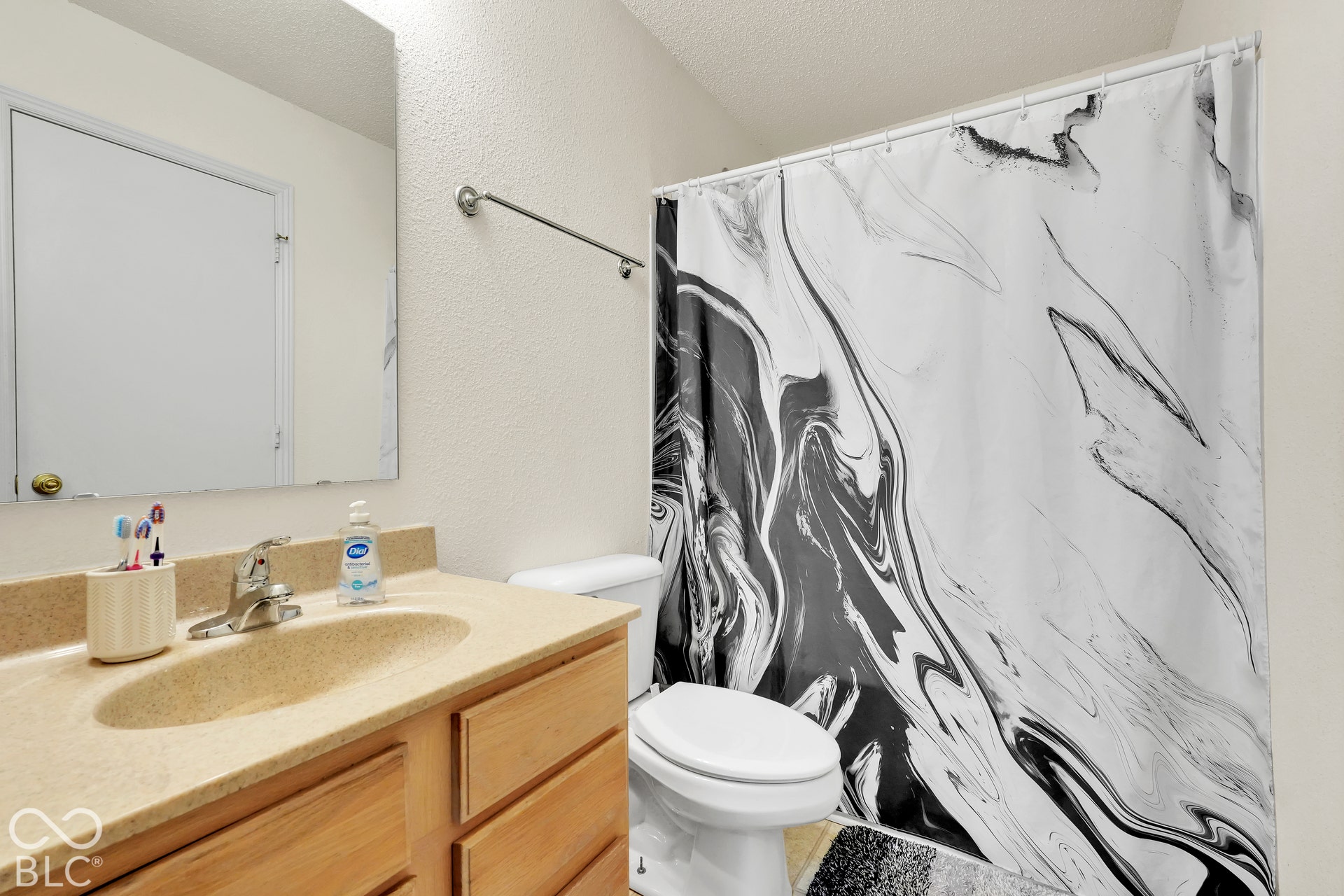 Vanity with a built-in sink, wood-finish cabinetry, and a large wall mirror
