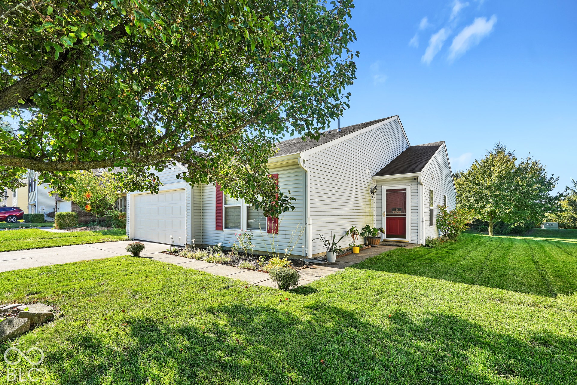 White siding exterior with a red entry door, attached garage, and concrete driveway