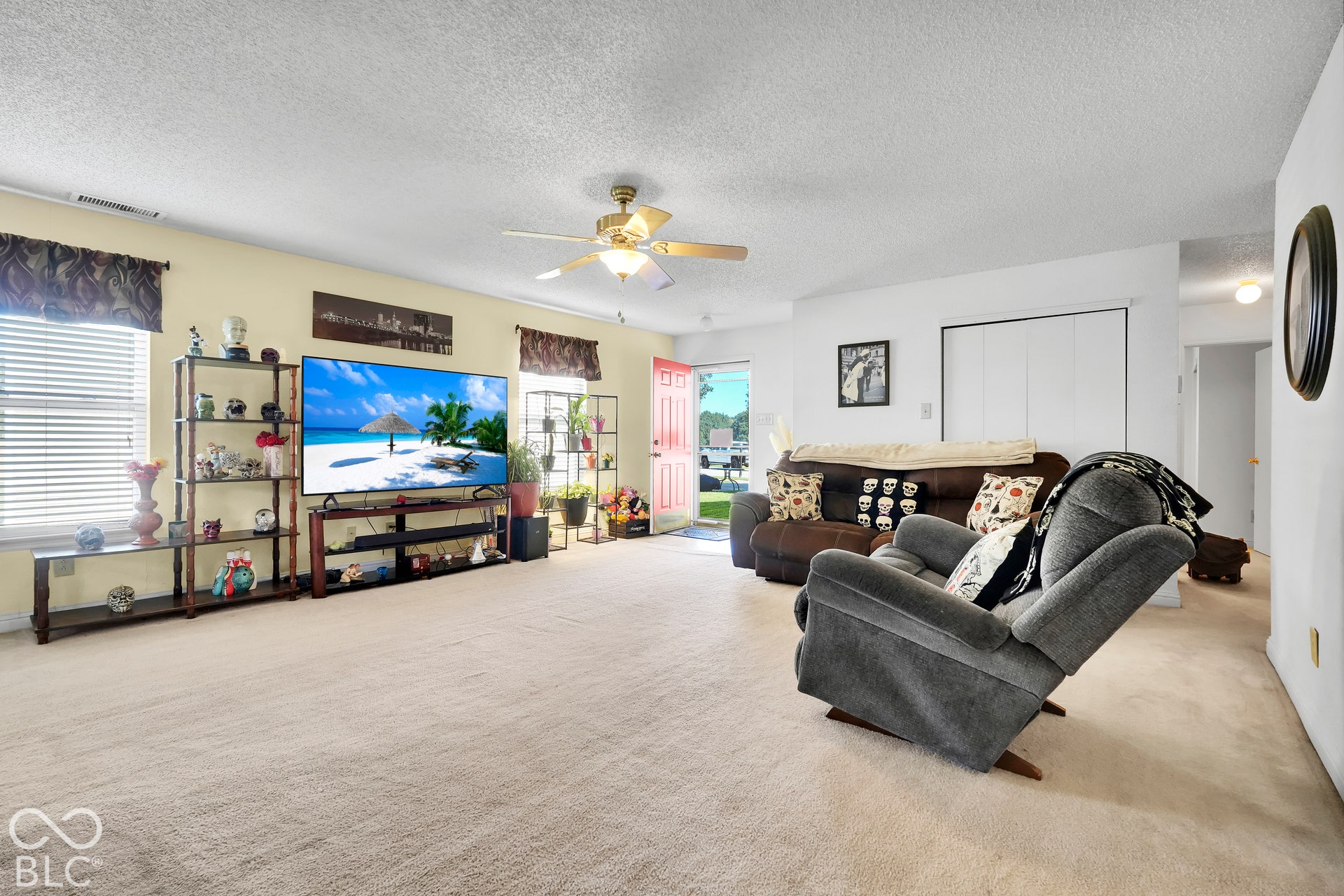 Spacious living area featuring light-toned carpeting and a ceiling fan