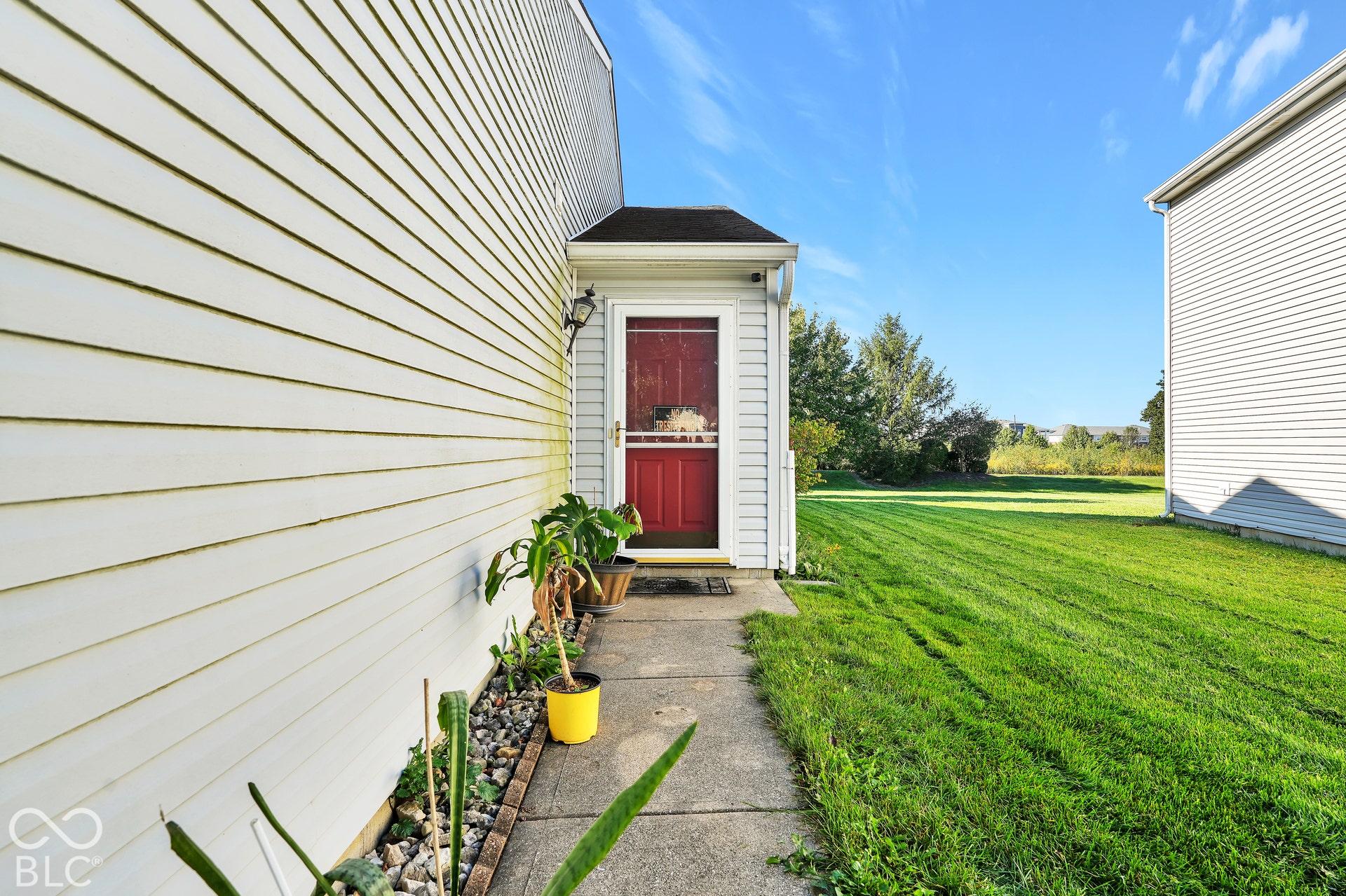 Siding exterior with a red entry door, covered entry, and concrete pathway