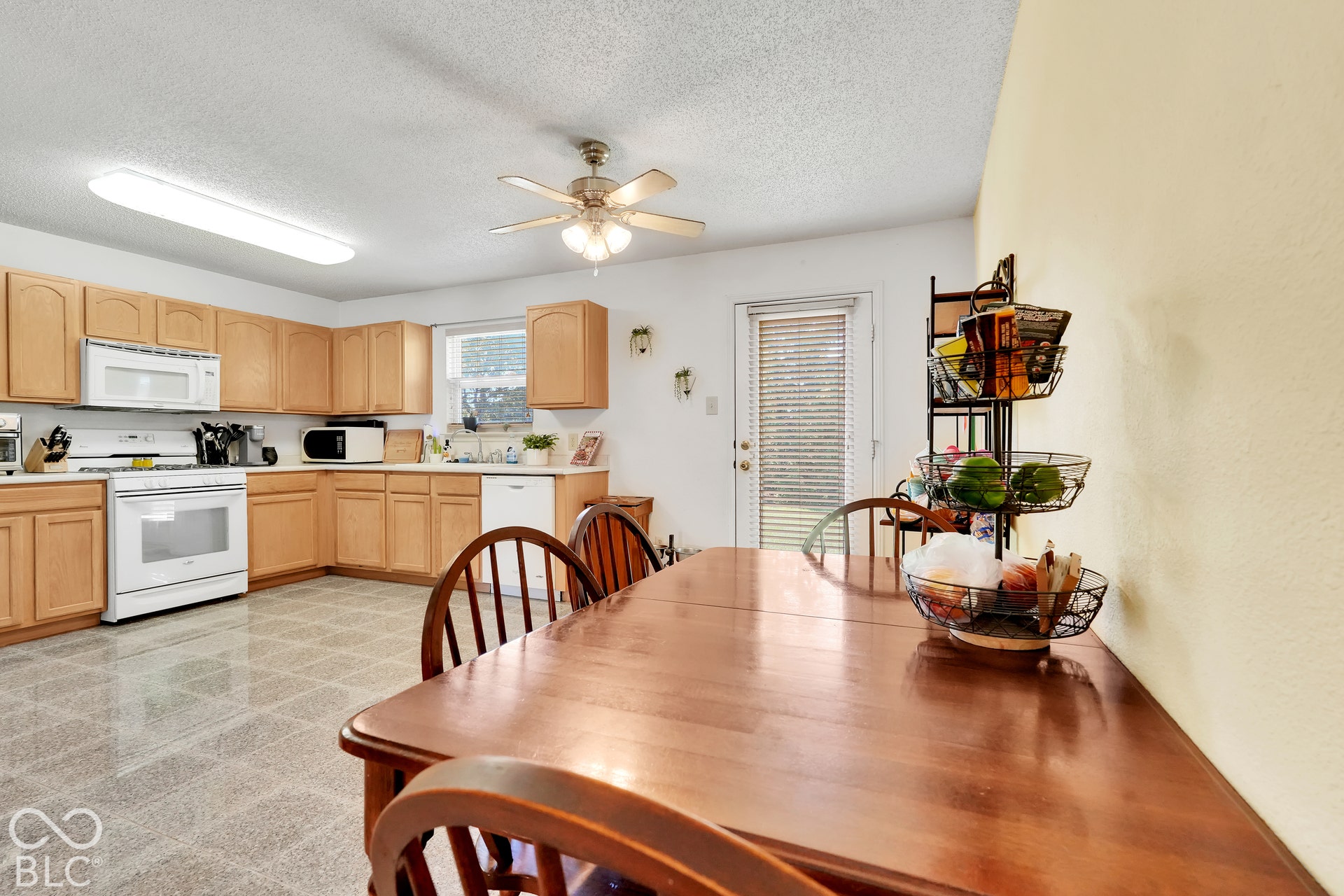 Kitchen featuring wood-finish cabinetry, white appliances, and a ceiling fan