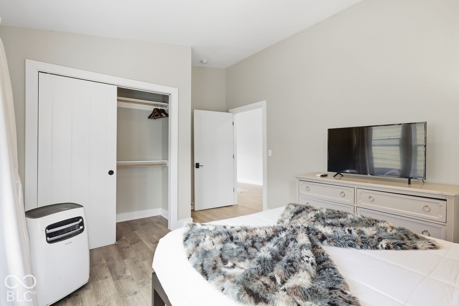 Light-toned wood-finish flooring, white sliding closet doors, and light gray wall paint