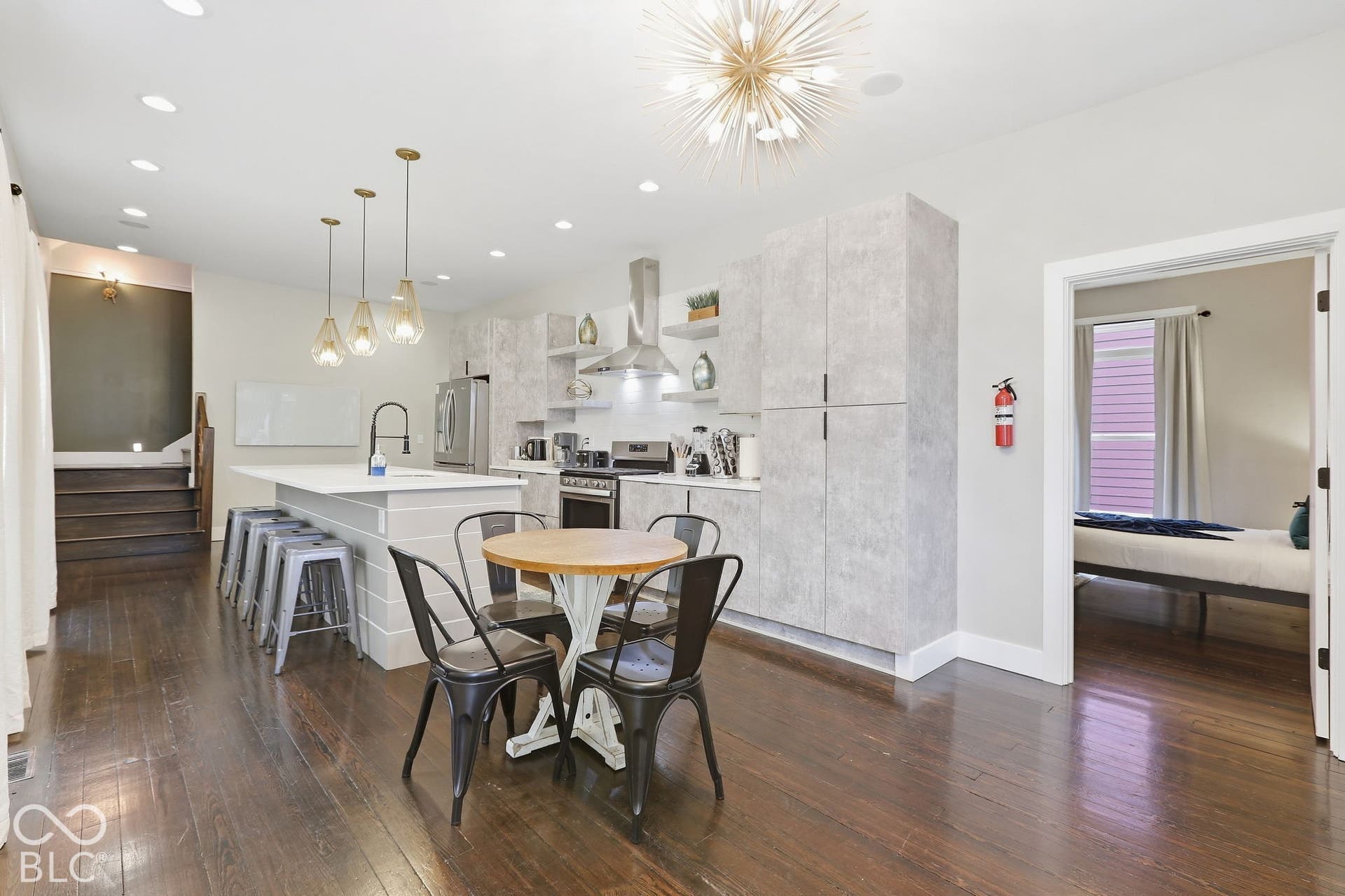 Hardwood flooring, central kitchen island with seating, pendant lighting, recessed lighting, and stainless steel appliances