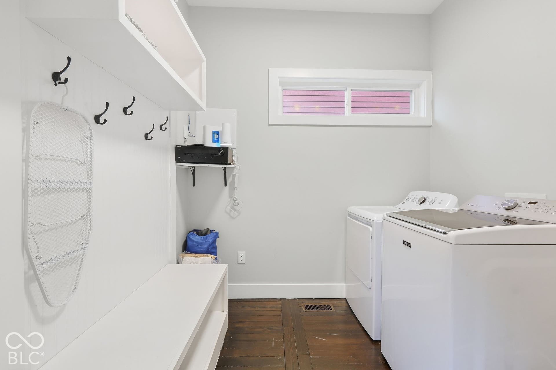 Dedicated laundry space featuring a side-by-side washer and dryer, built-in bench with storage, upper shelving, and dark wood-finish flooring