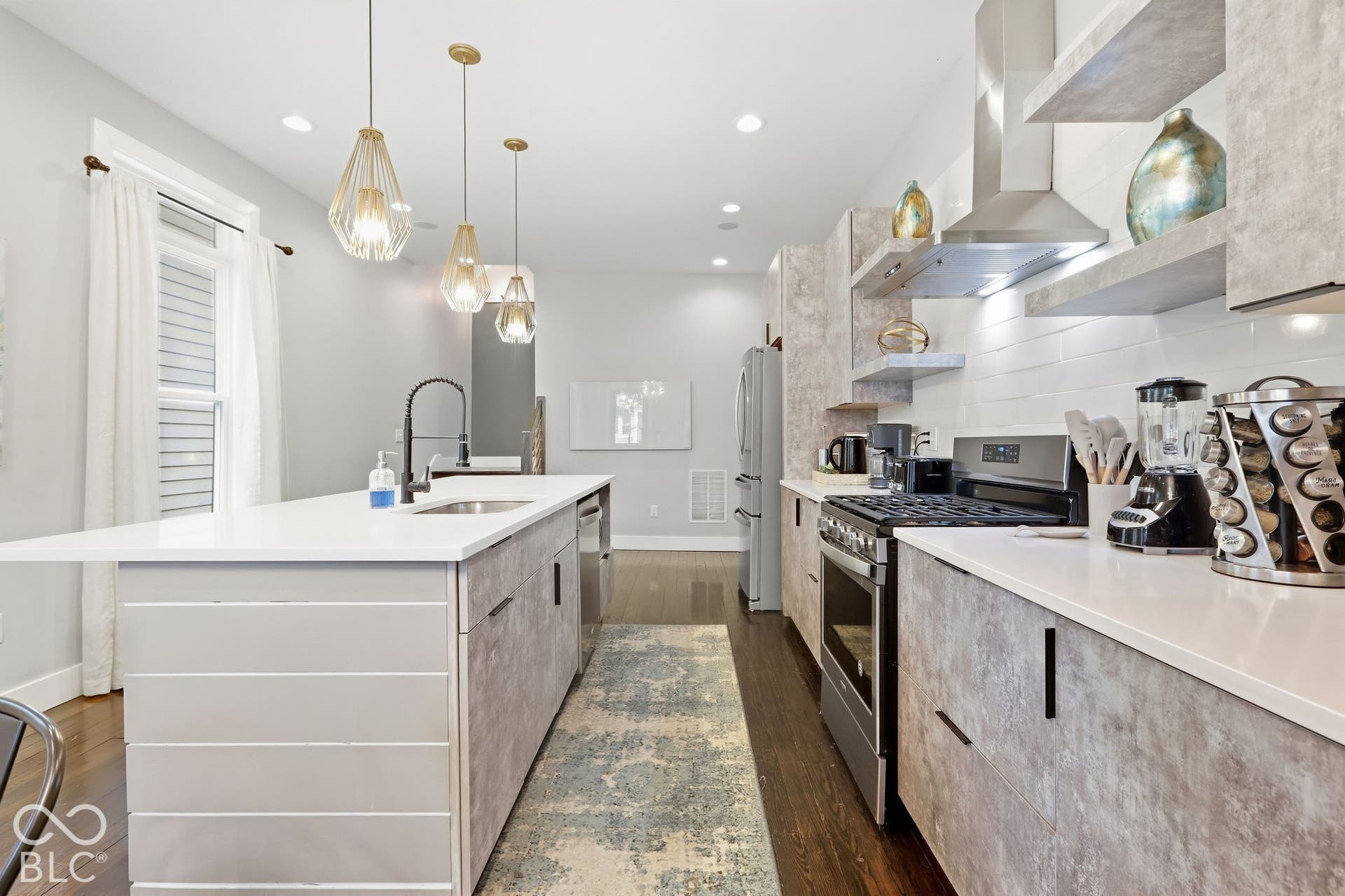Kitchen featuring an expansive island with a built-in sink, white countertops, and contemporary pendant lighting