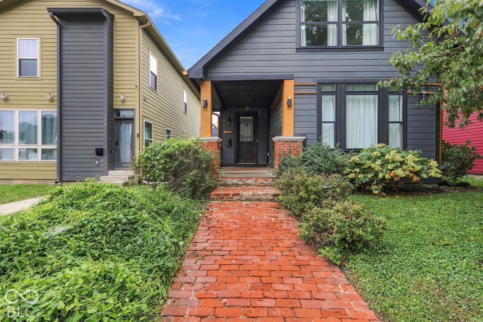 Brick pathway leading to an inviting front porch with a dark-paneled door