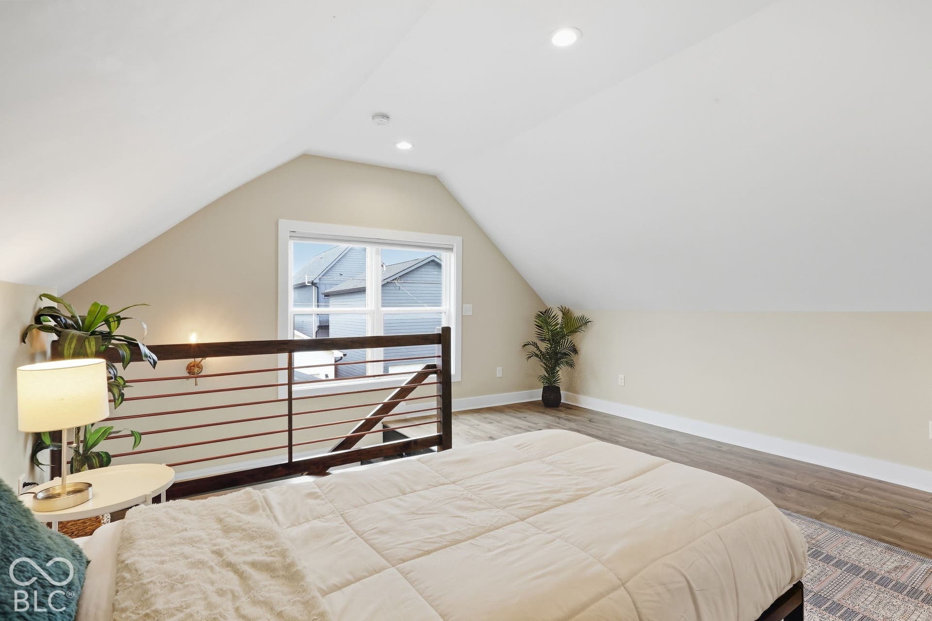 Sloped ceilings, wood-finish flooring, recessed lighting, and a modern horizontal railing