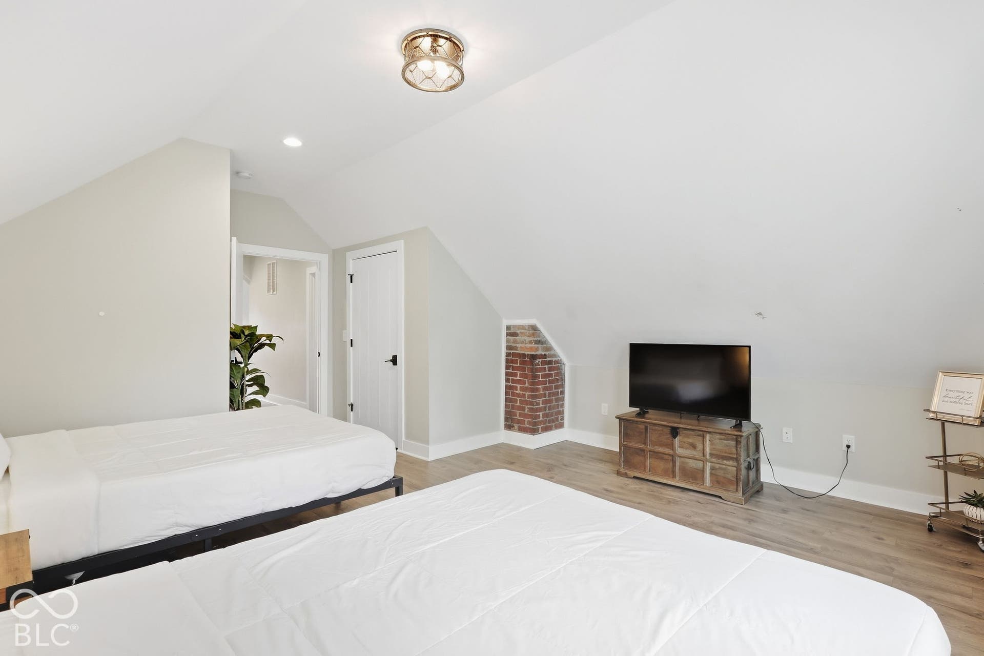 Sloped ceilings with recessed lighting, wood-finish flooring, exposed brick architectural detail, and a flush mount ceiling fixture