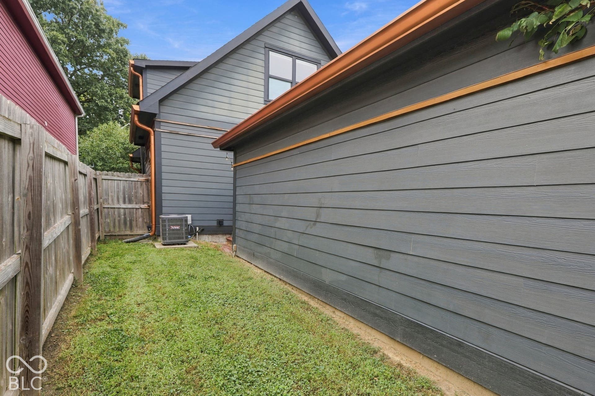 Exterior featuring horizontal siding, copper-finish gutters, and a compact grass area