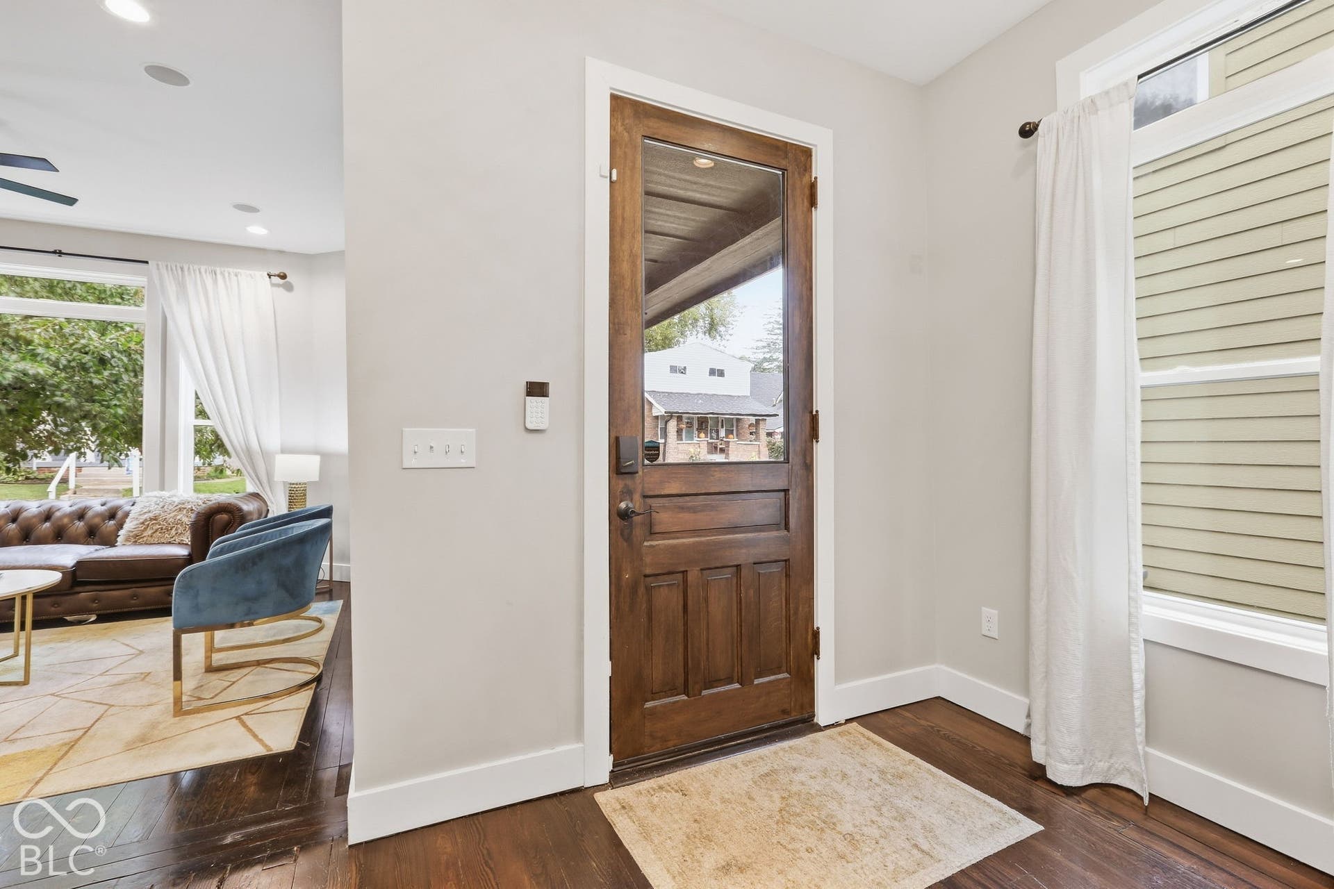 Wood-finish flooring, white baseboards, and a glass-paneled entry door