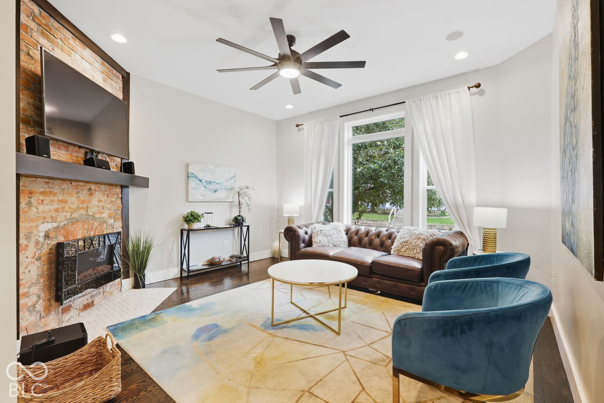 Exposed brick fireplace with a wood mantel, dark wood-finish flooring, recessed lighting, and a contemporary ceiling fan