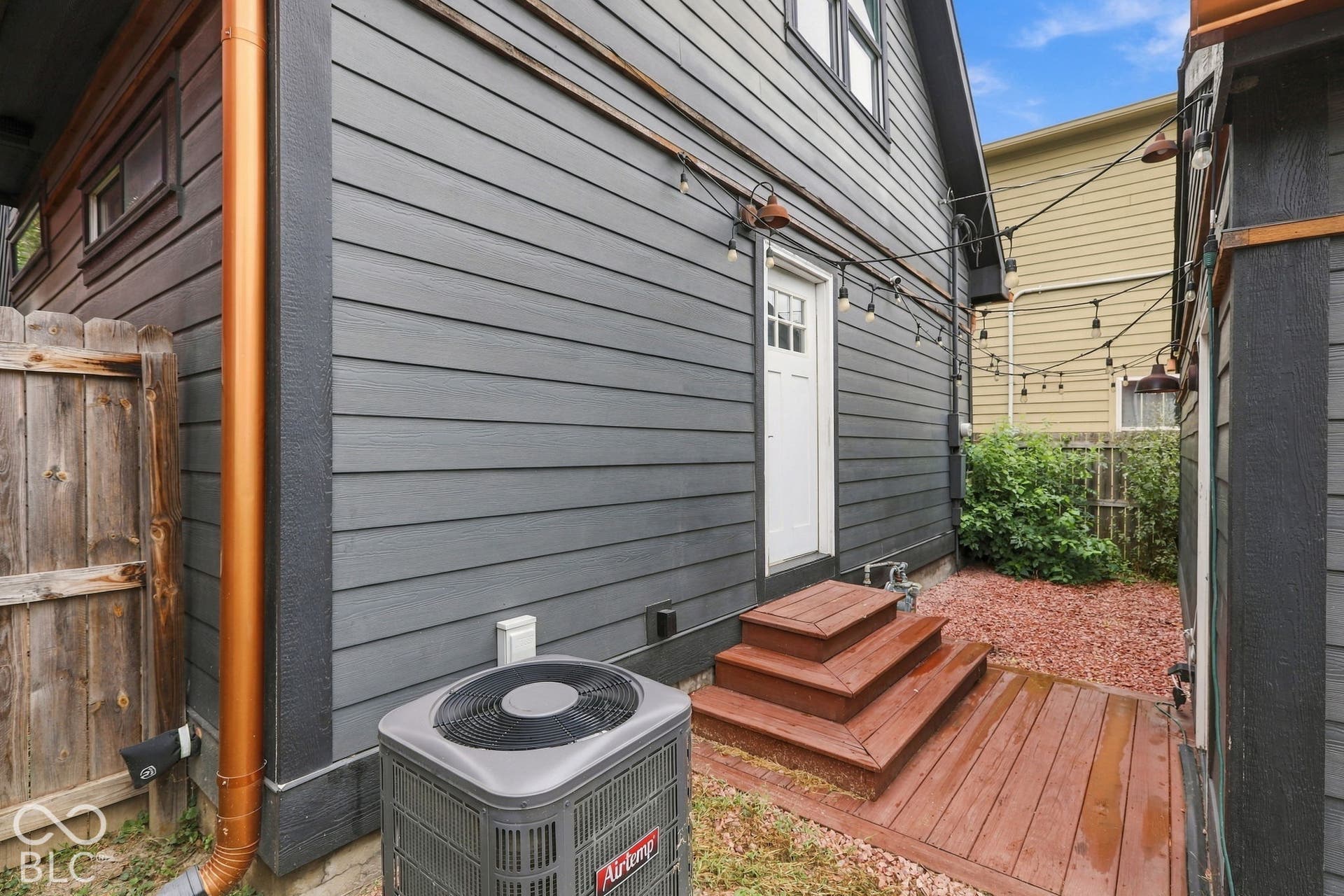 Siding with dark finish, exterior door with grid window, wood-finish decking, and multi-tiered wood-finish steps