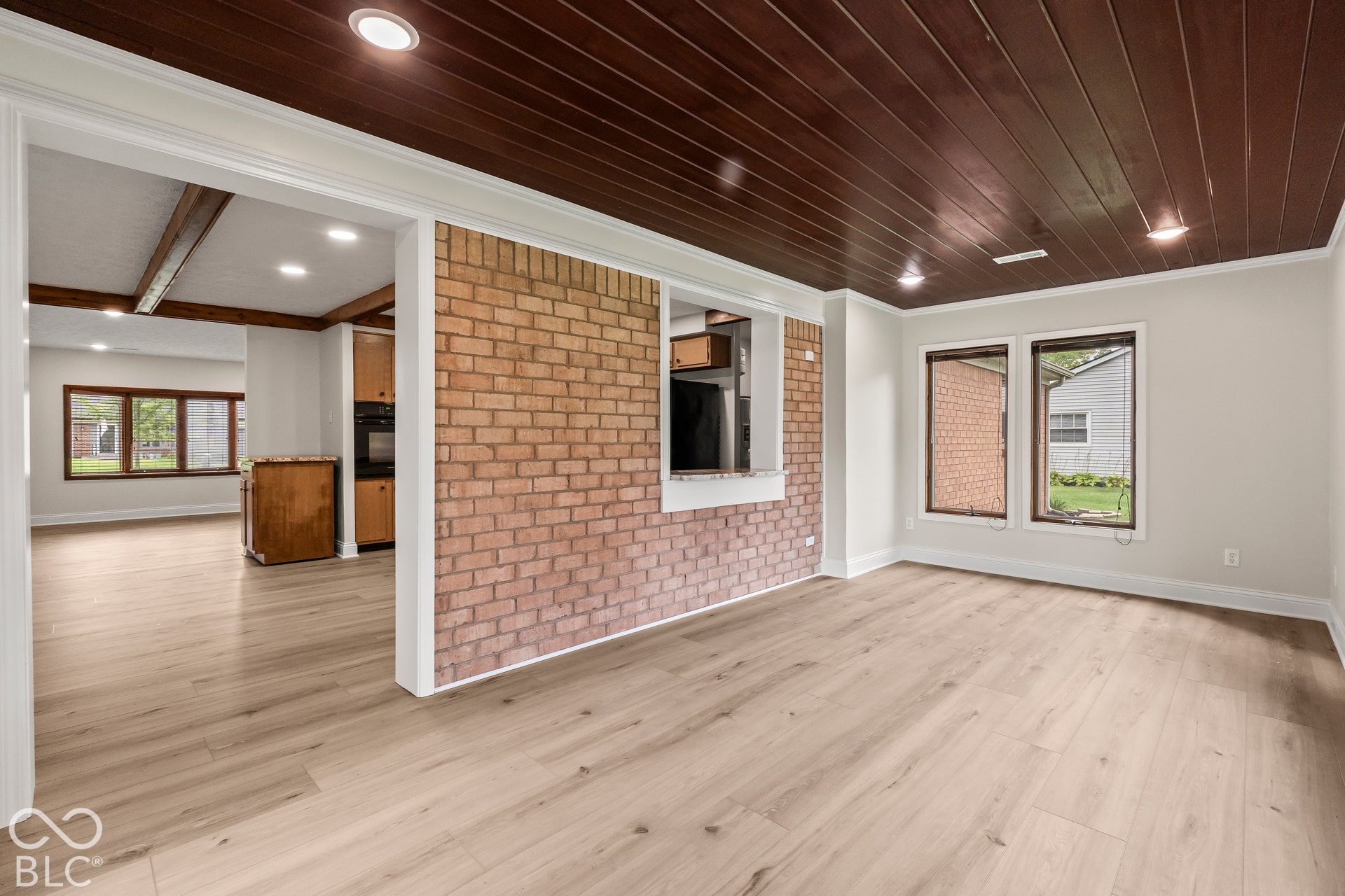 Wood-finish flooring, recessed lighting, exposed brick accent wall, white trim, and wood plank ceiling