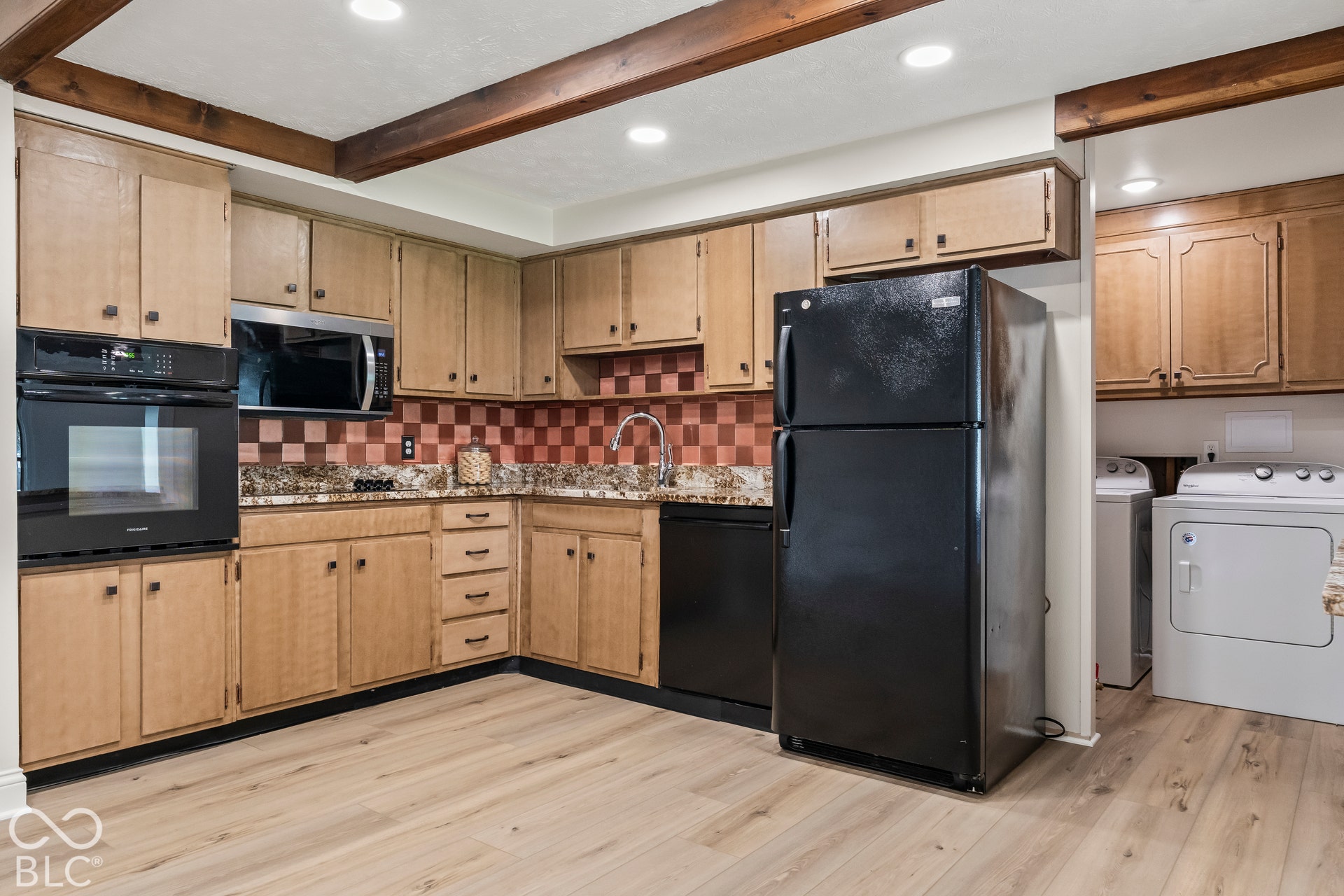 Kitchen featuring wood-finish cabinetry, built-in oven, integrated microwave, and granite-style countertops