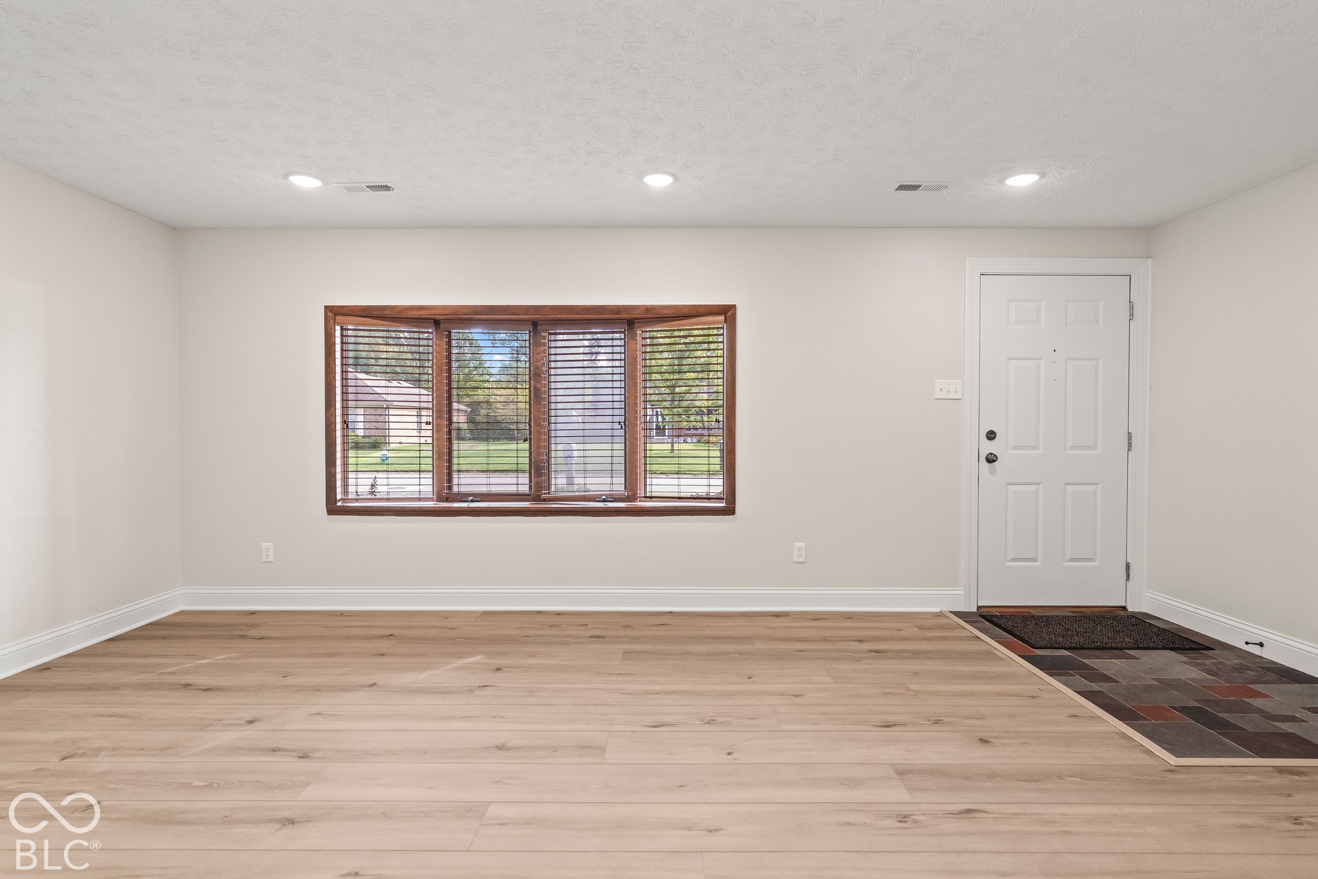 Recessed lighting, wood-finish flooring, white walls, and a bay window with a wood frame