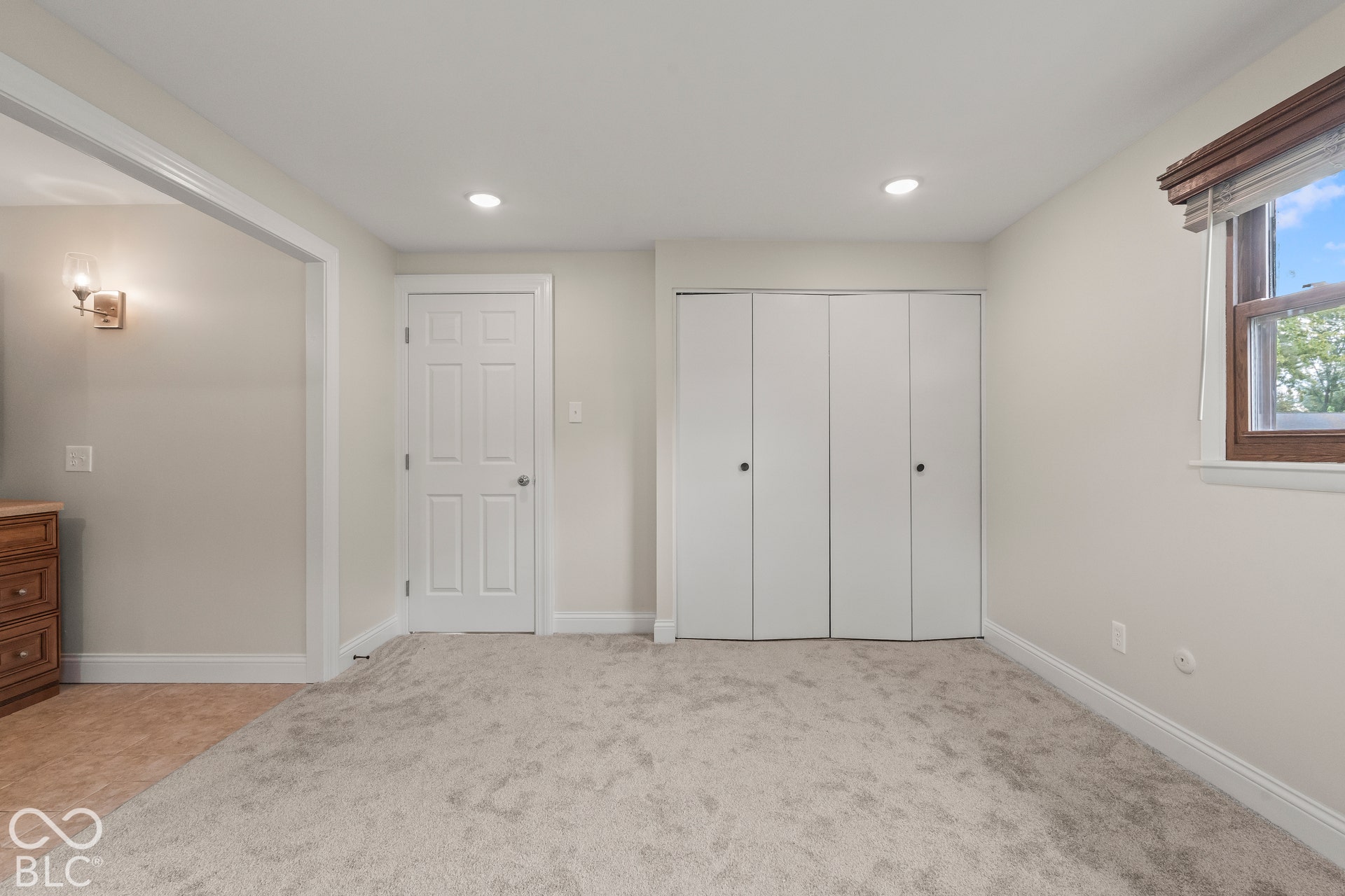 Recessed lighting, light-toned carpeting, and a window with blinds