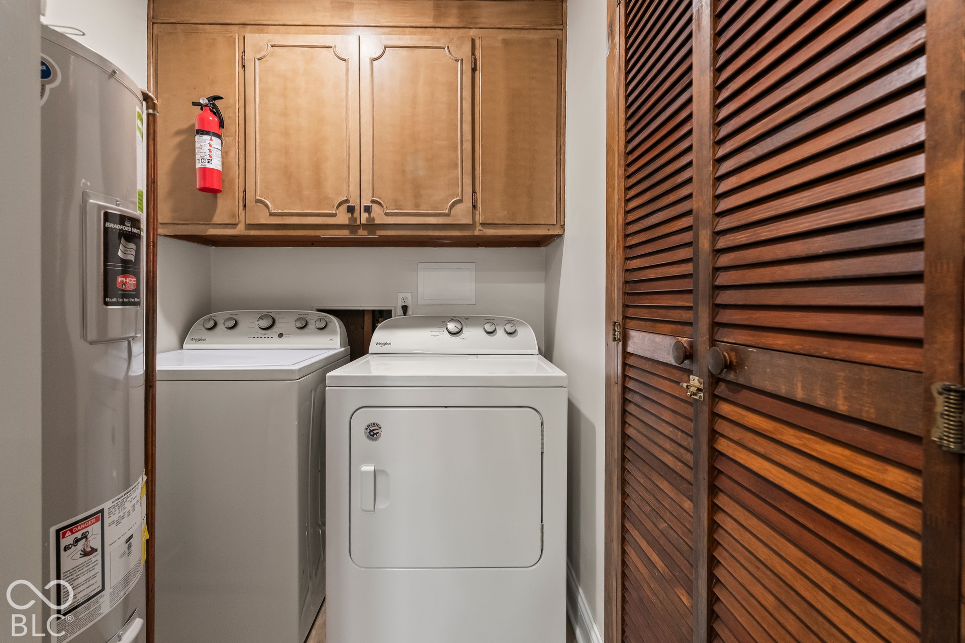 Dedicated utility area featuring a top-load washer, front-load dryer, upper cabinetry, and louvered doors