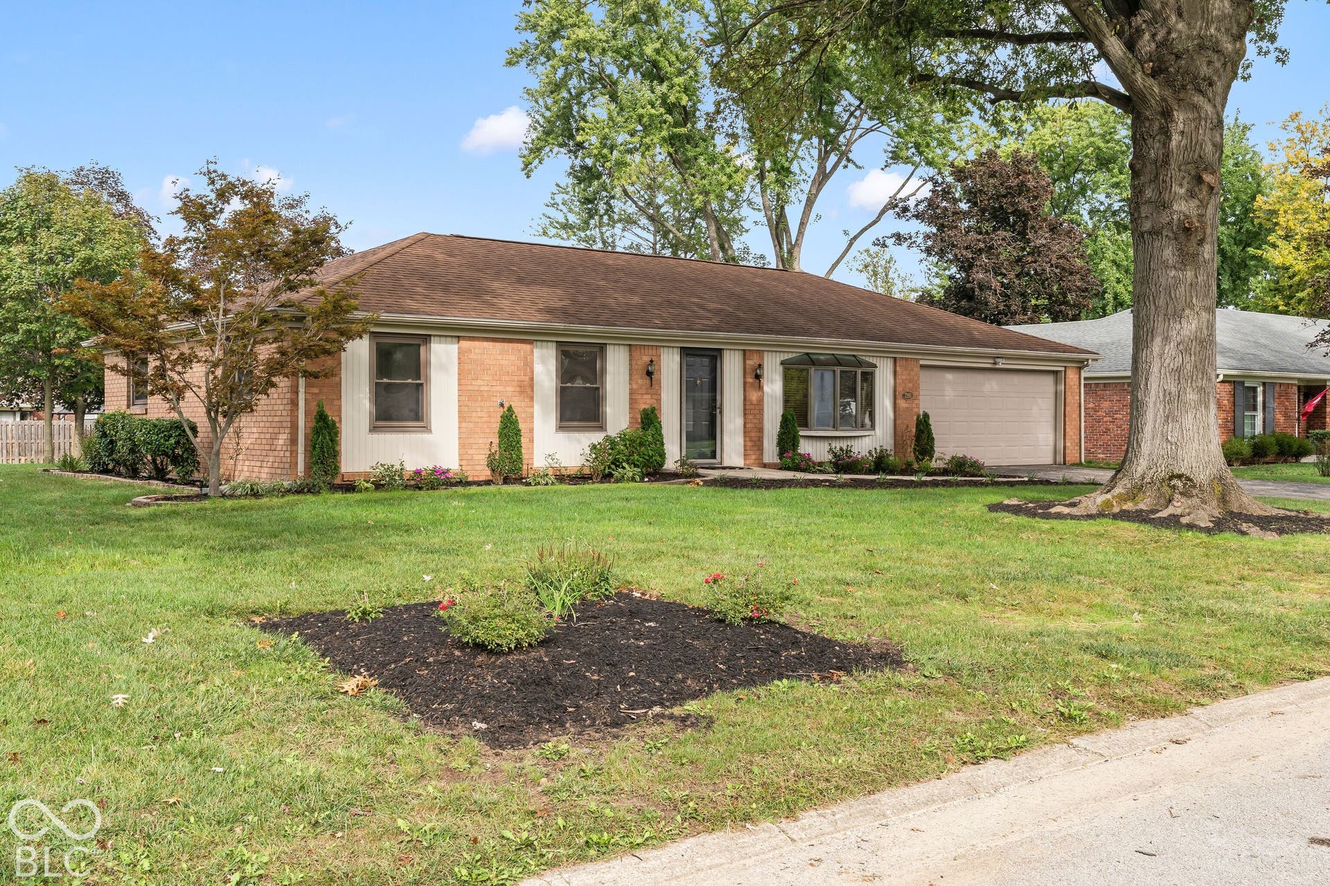 Brick exterior with a prominent bay window, attached garage, and mature landscaping