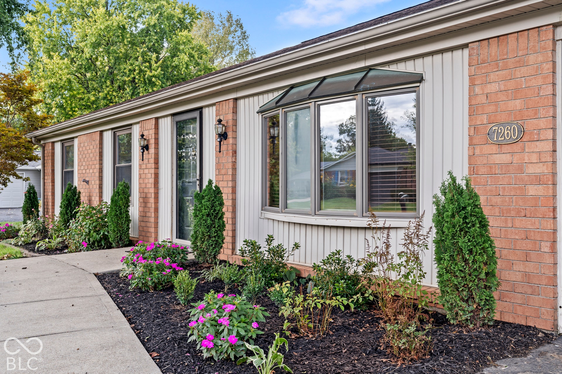 Brick and vertical siding exterior with a bay window and decorative awning