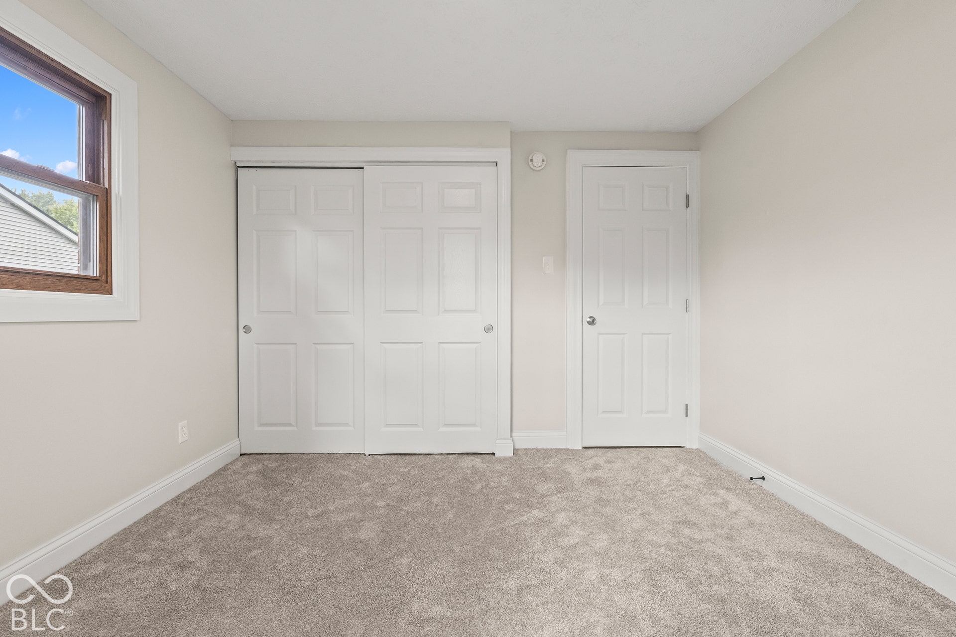 Bedroom 3Soft neutral carpeting, white trim, and a window with a wood frame