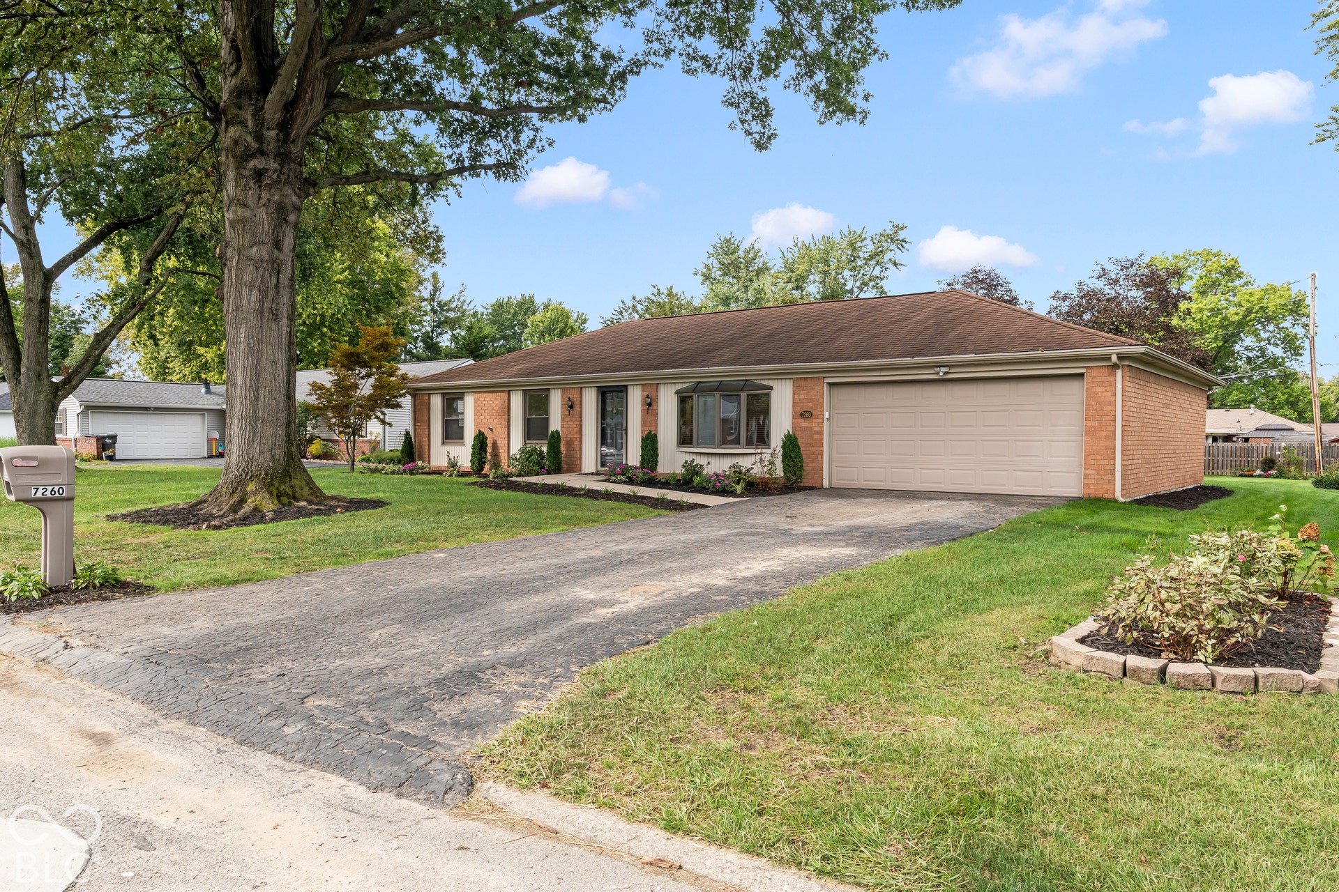 Brick exterior with a prominent bay window, attached two-car garage, and mature landscaping