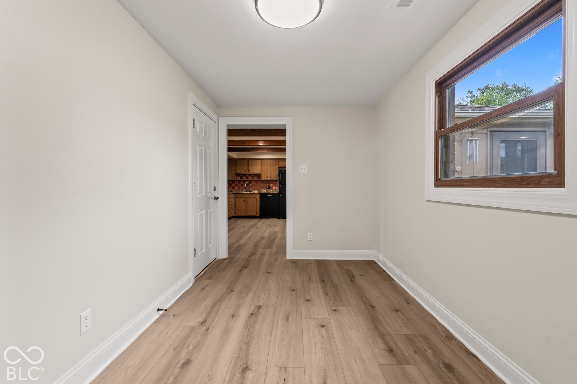 Can be used as office or rec roomWood-finish flooring, white walls, and a window with wood trim