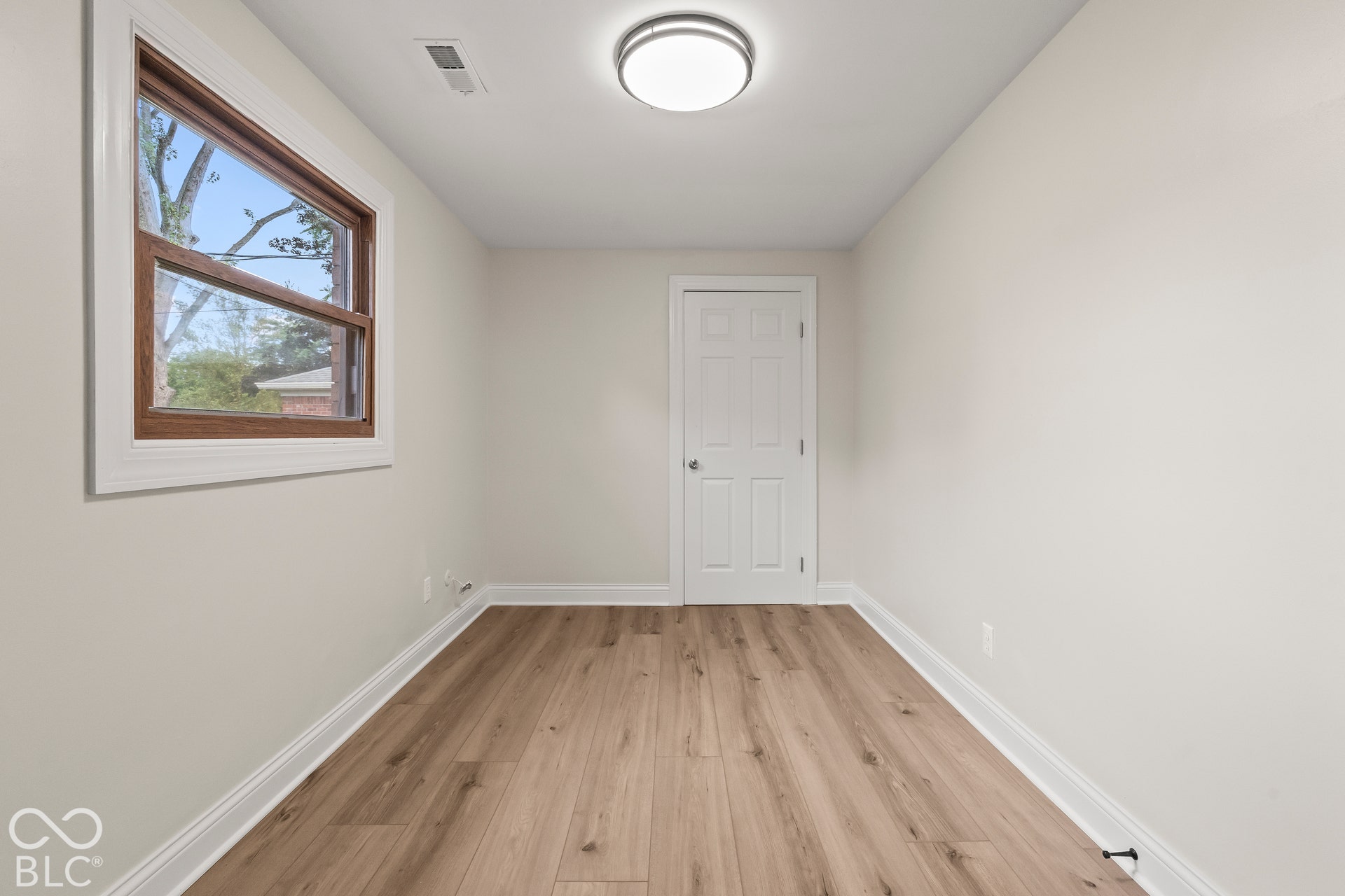 Wood-finish flooring, white trim, recessed lighting, a multi-pane window with wood-finish framing, and a white paneled door