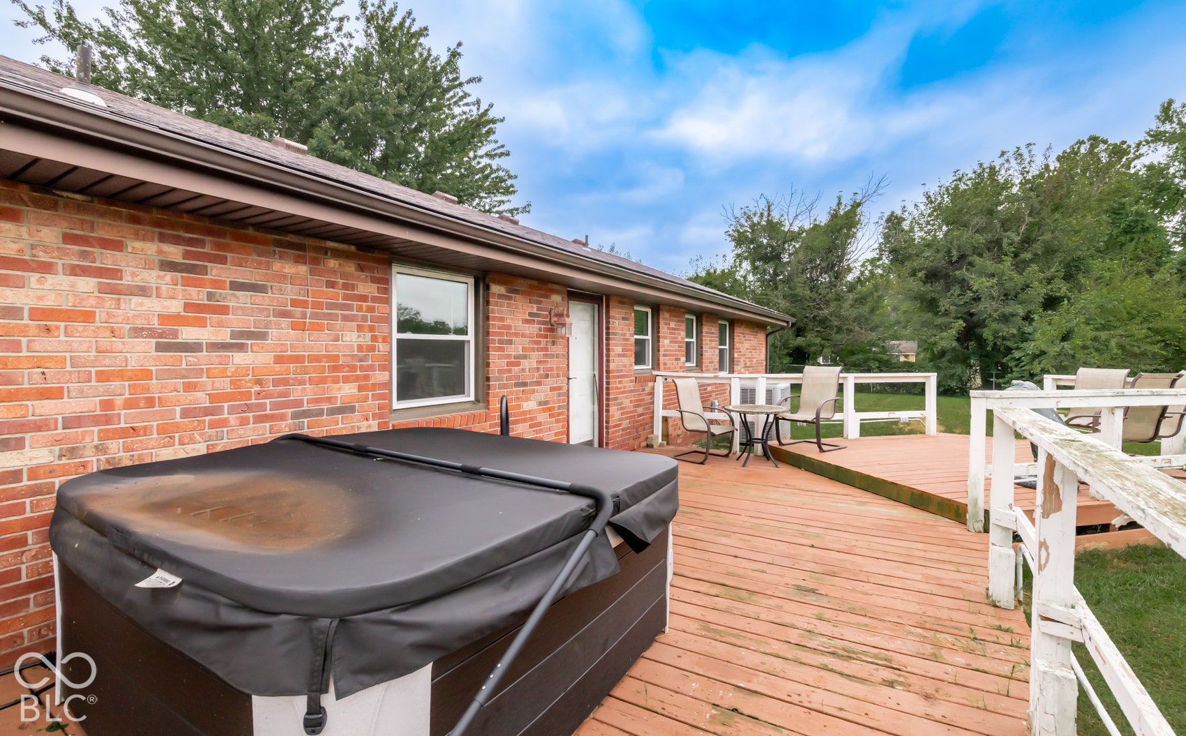 Expansive wood deck with railing, brick exterior, and an exterior door