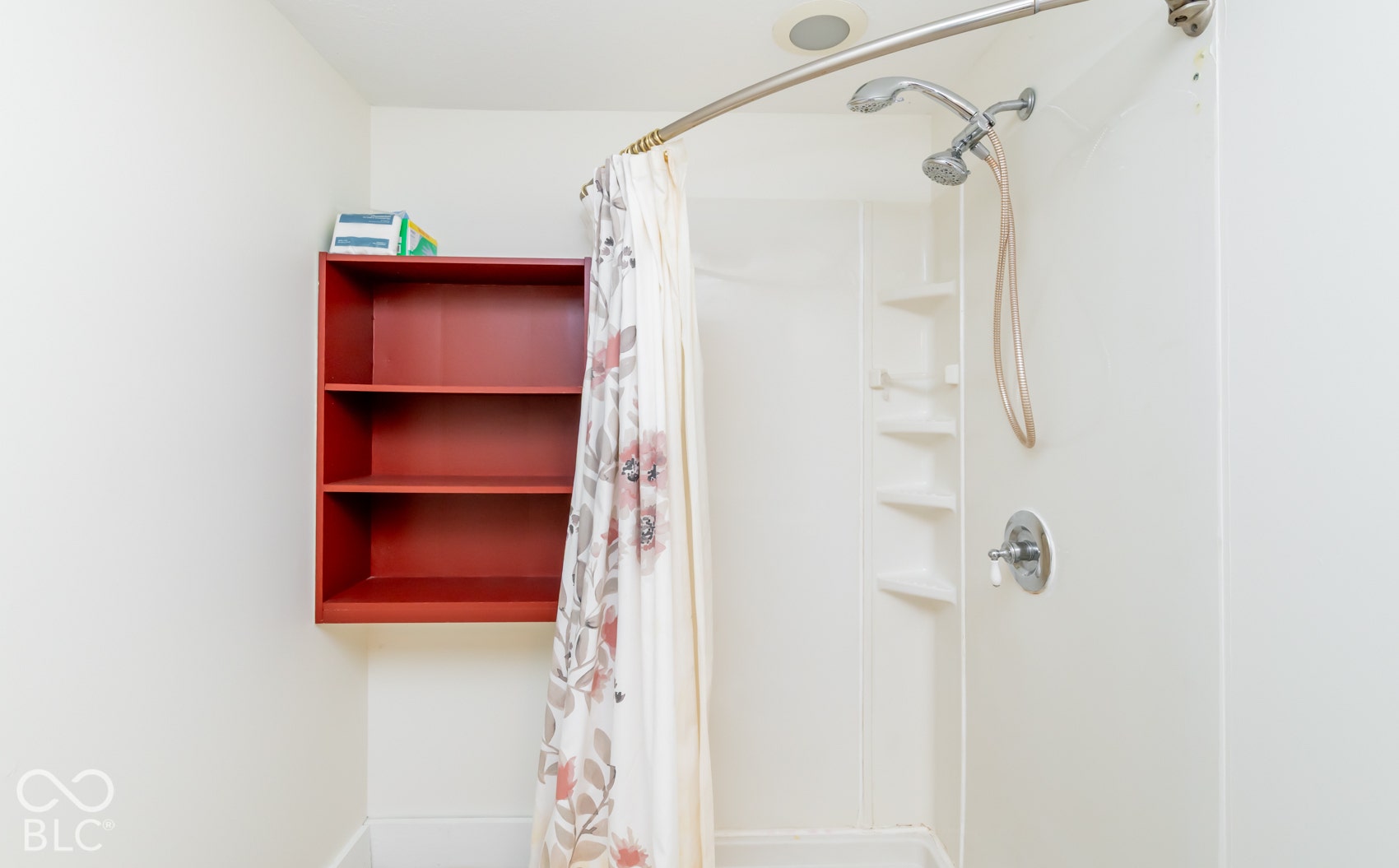 Shower with a curved shower rod, integrated shelving, and a wall-mounted shower head