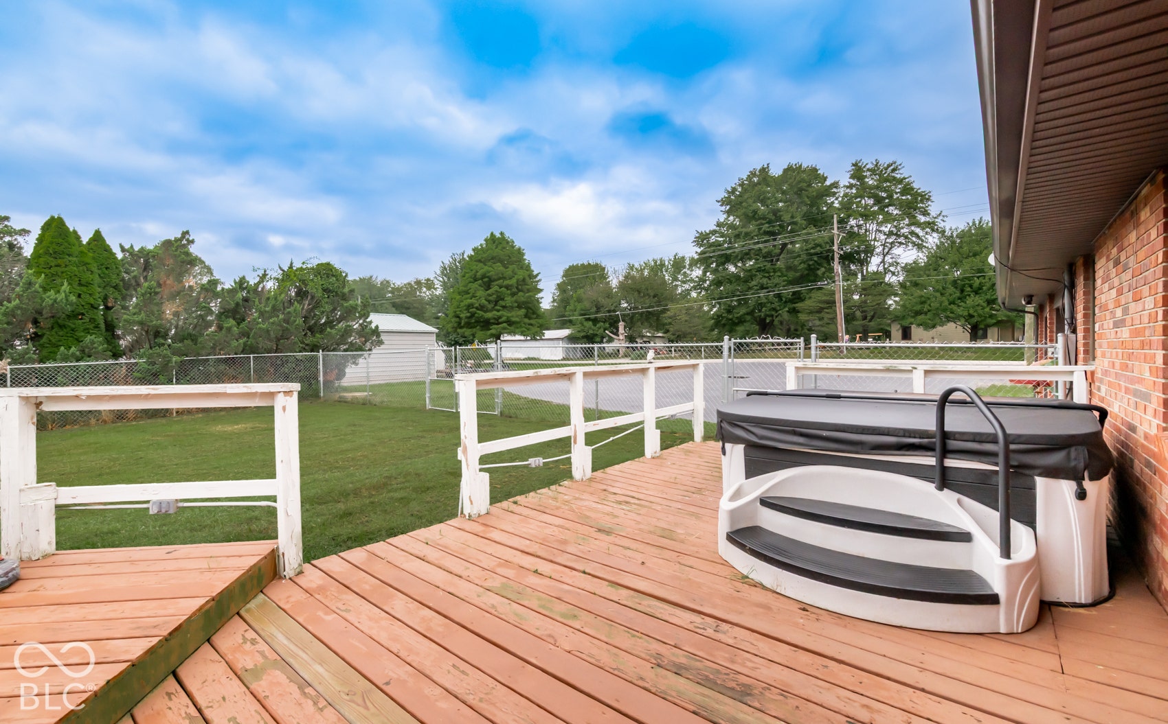 Wood-finish deck with white railing and integrated hot tub with steps