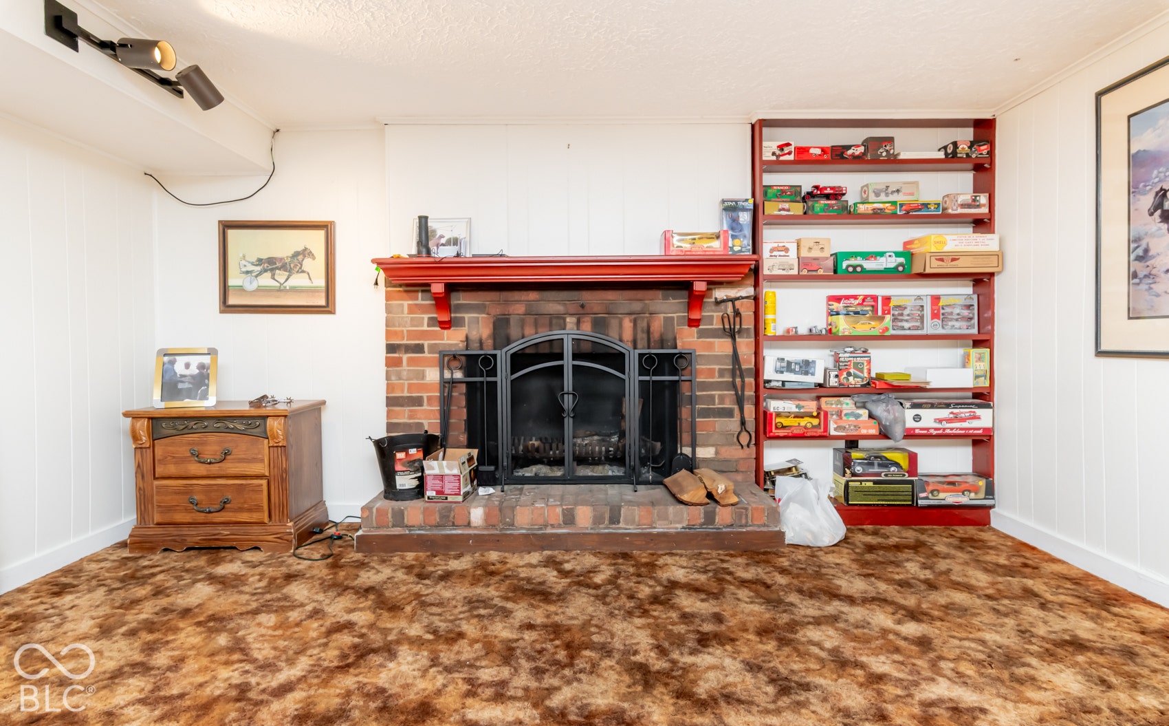 Brick fireplace with a black metal screen, a red mantel, and an integrated built-in shelving unit