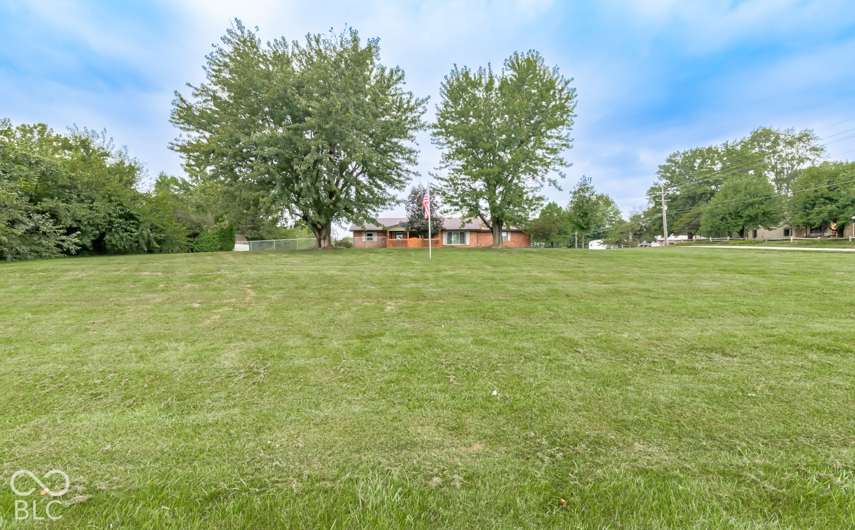 Expansive front yard featuring a manicured lawn and mature trees