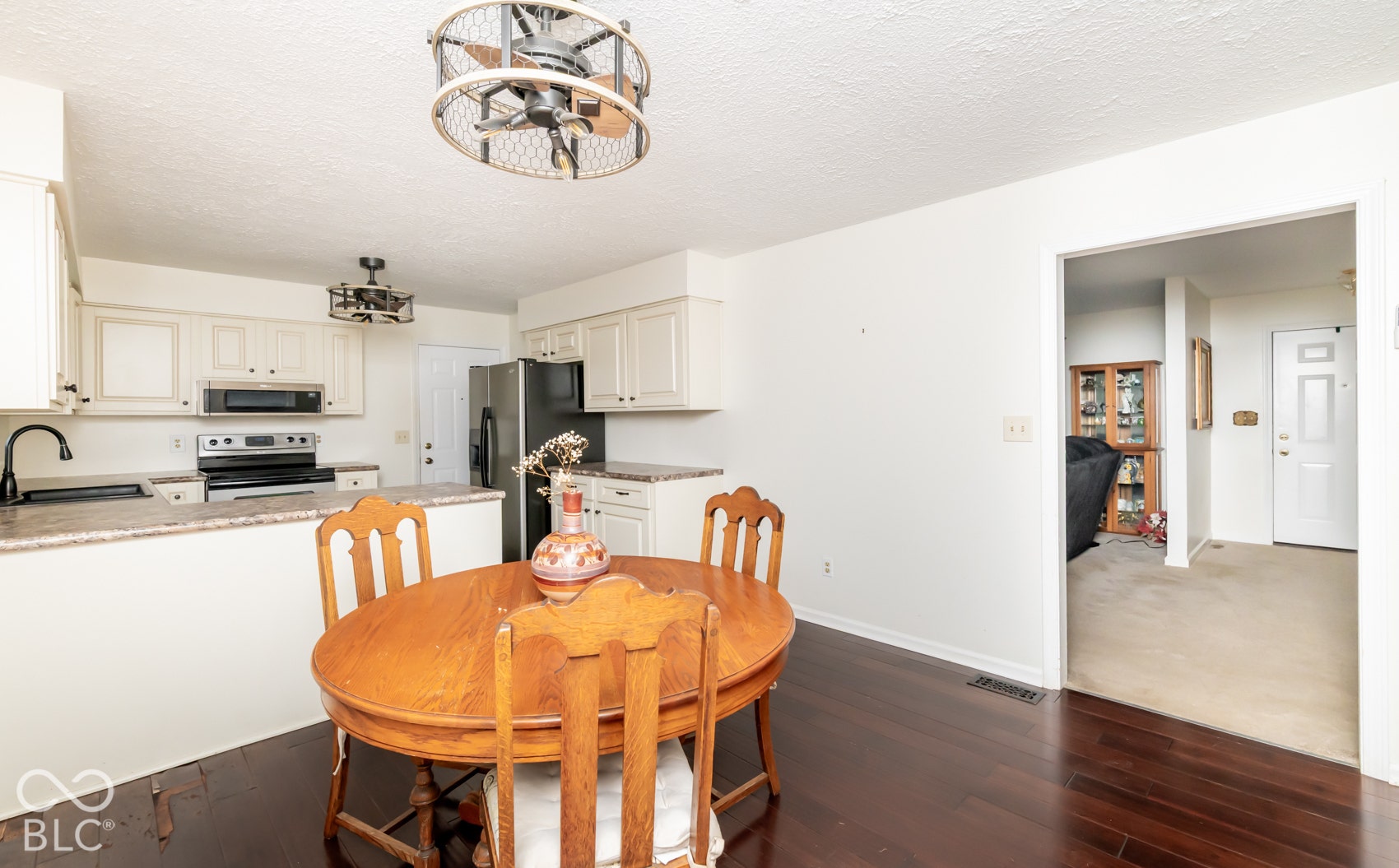 Wood-finish flooring, white cabinetry, integrated stainless steel appliances, and a built-in breakfast bar