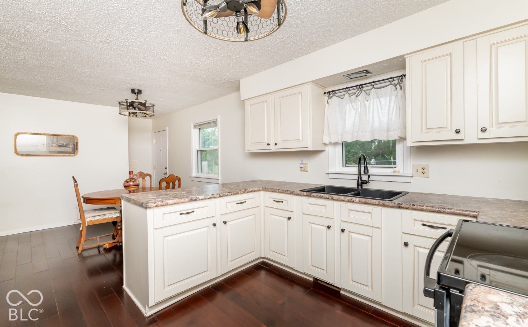 Kitchen with white cabinetry, dark countertop, and dark-finish flooring