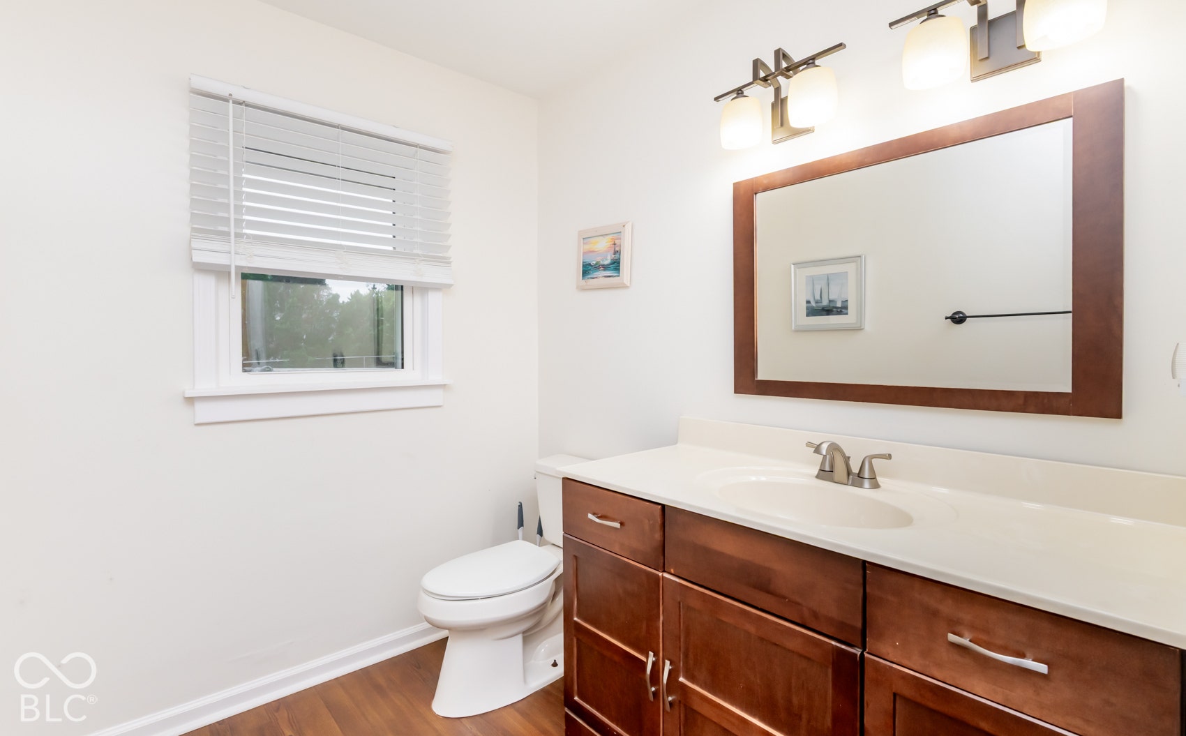 Wood-finish flooring, white walls, and a window with blinds
