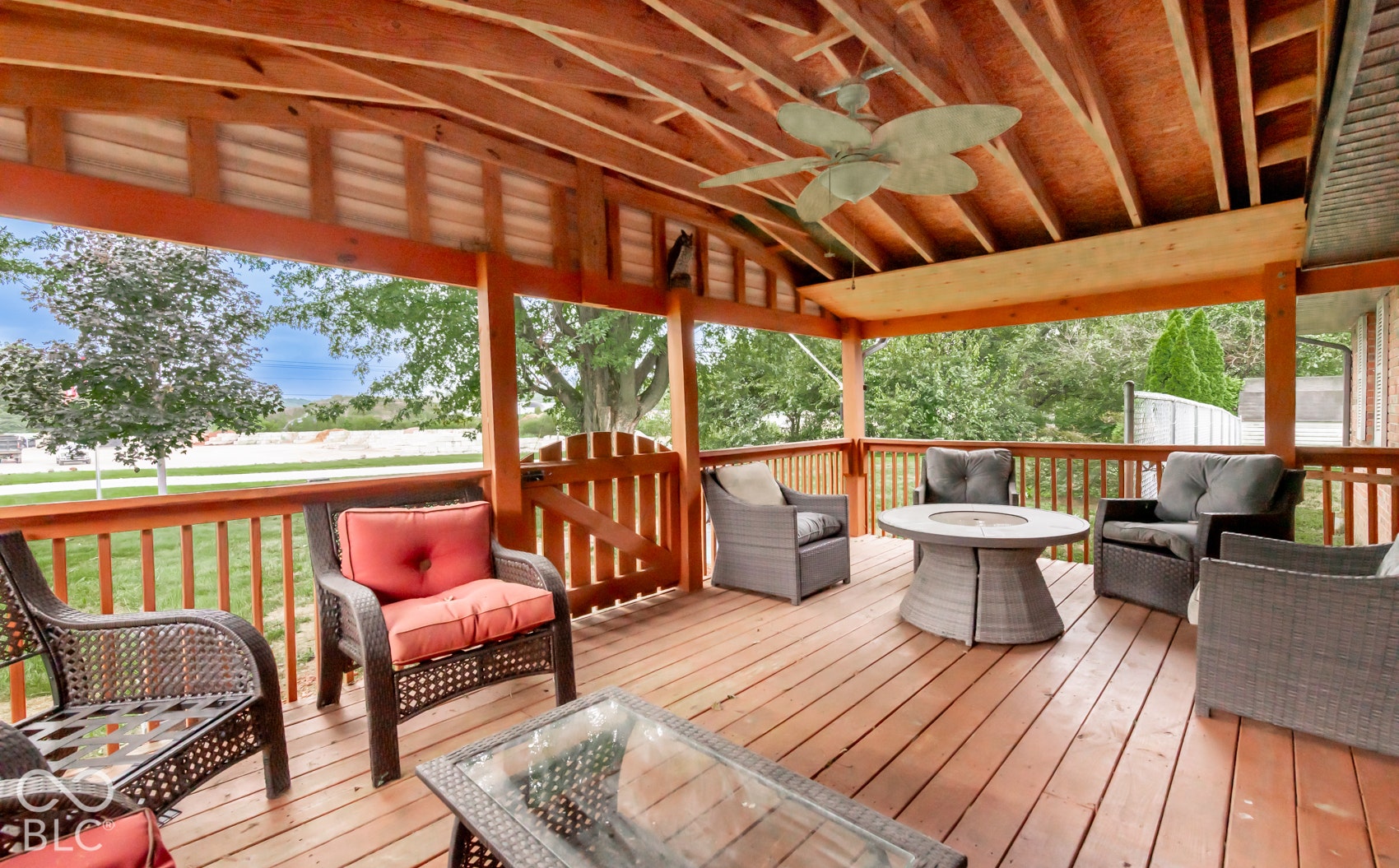 Covered deck featuring wood decking, exposed wood beam ceiling, ceiling fan, and wooden railing