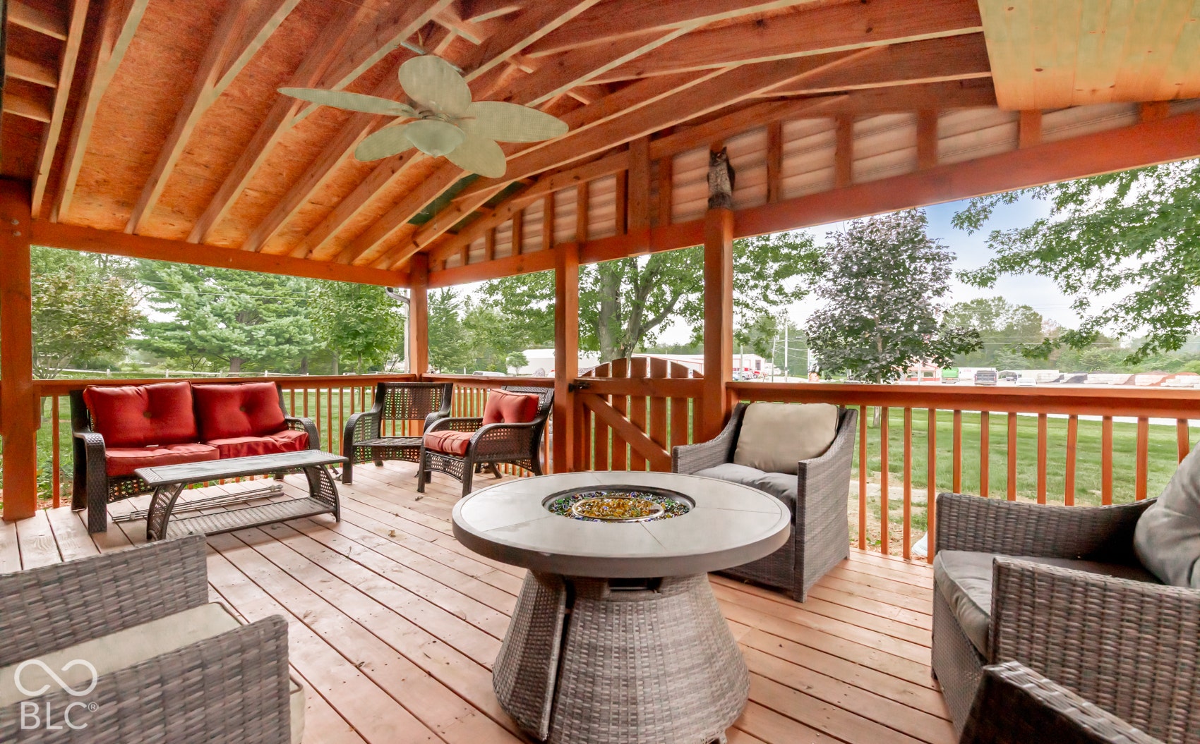Covered outdoor deck with exposed wood beam ceiling, wood-finish flooring, and a ceiling fan