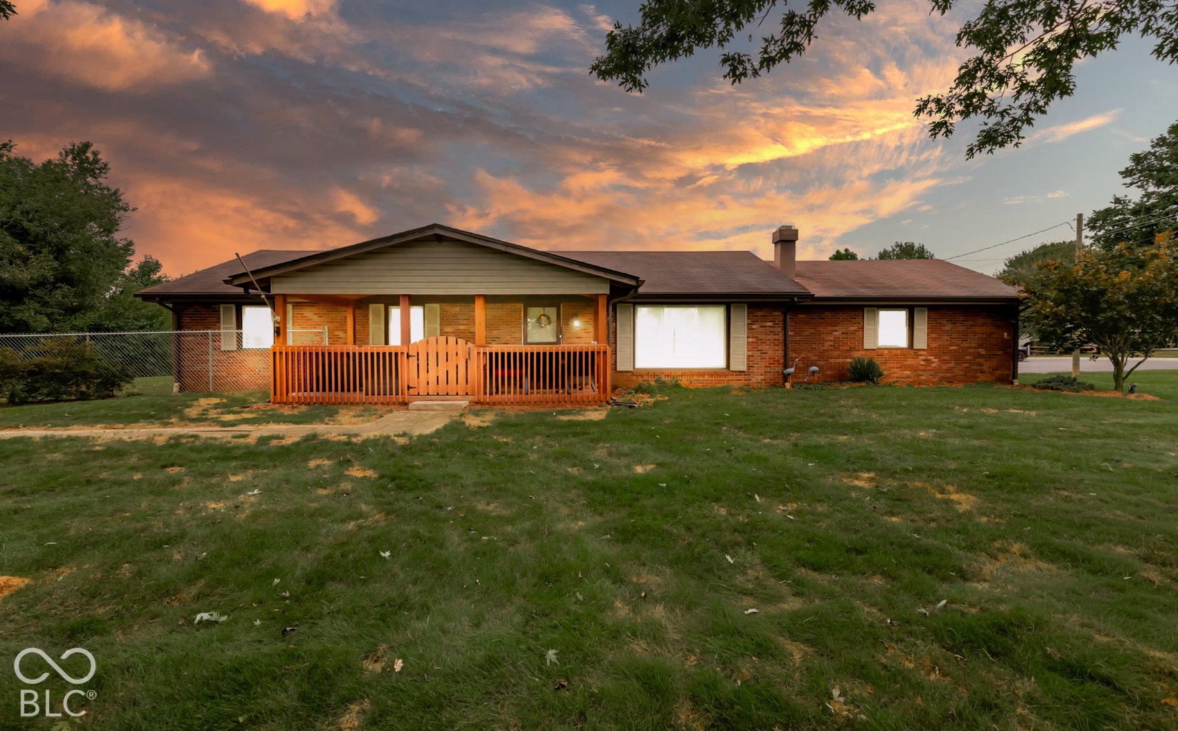 Brick exterior featuring a wood-slat front porch with fencing, an attached roofline, and visible windows