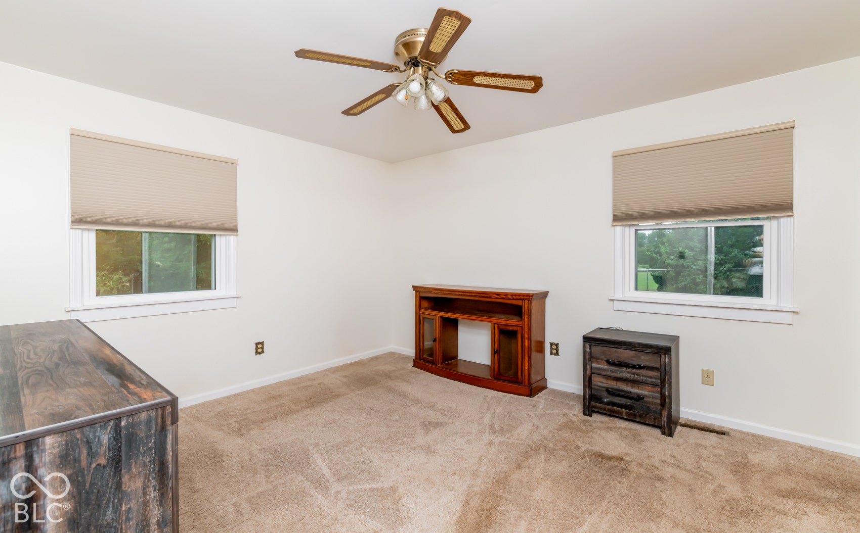 Textured carpeting, two windows with blinds, and a ceiling fan with integrated lighting