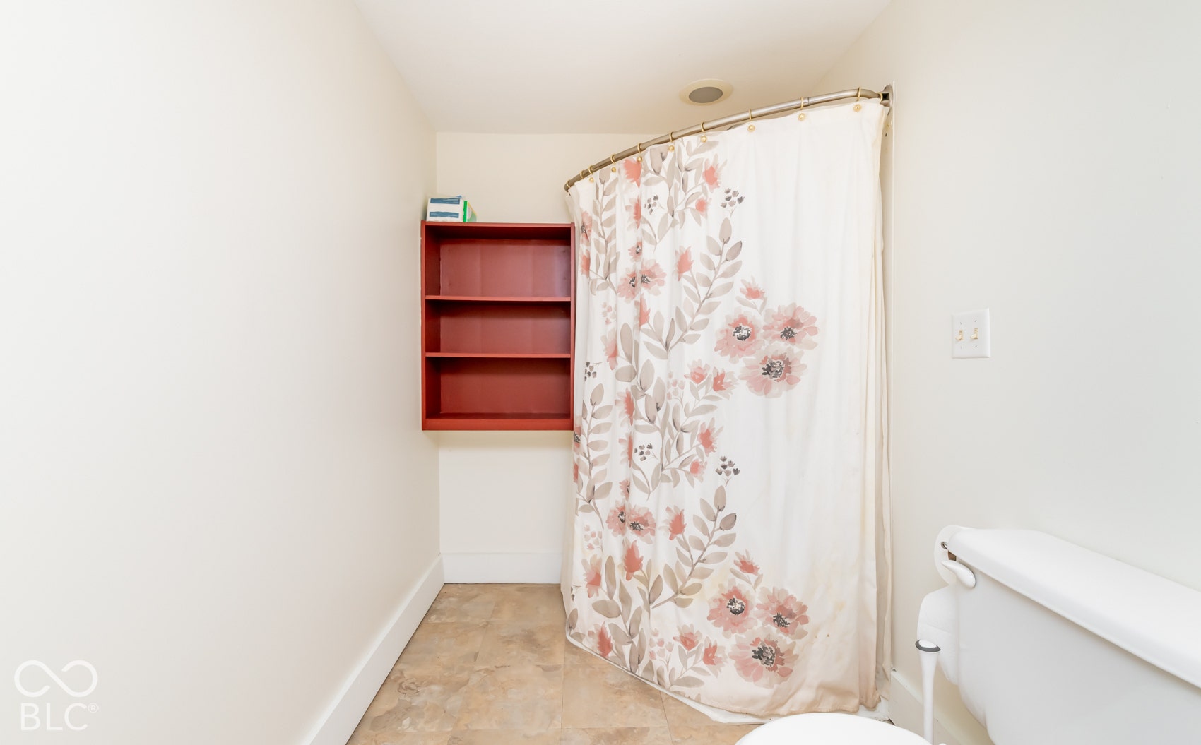 Recessed lighting fixture, light-toned wall paint, built-in shelving unit, toilet, and tiled flooring